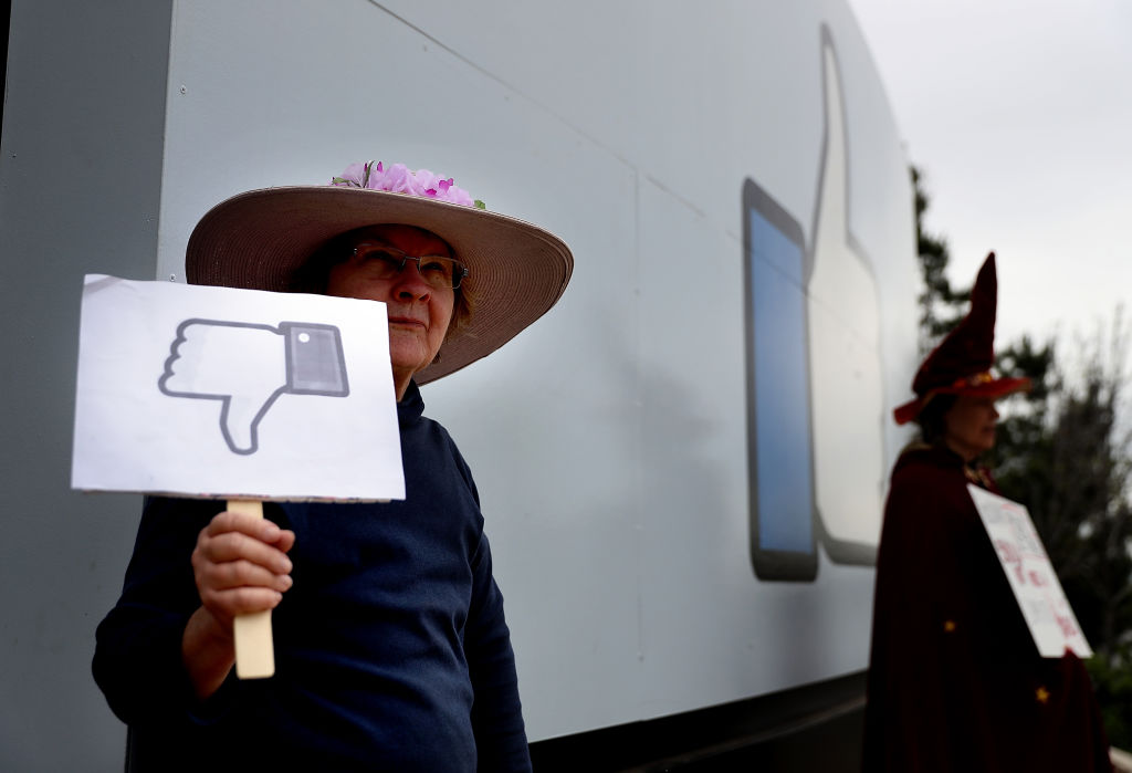 FILE PICTURE: A protester with the group "Raging Grannies" holds a sign during a demonstration outside of Facebook headquarters on April 5, 2018 in Menlo Park, California. (Photo by Justin Sullivan/Getty Images)