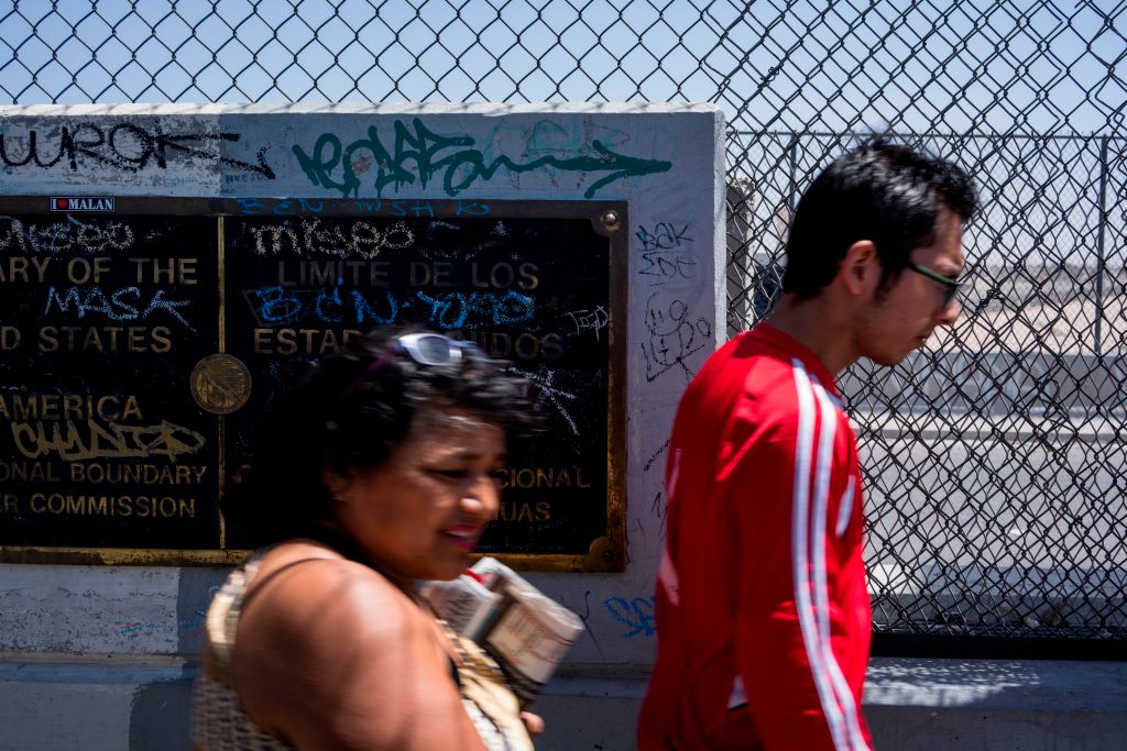 Pedestrians pass a placard marking the dividing line of the US-Mexico Border on the Cordova Americas Bridge between El Paso, Texas and Ciudad Juarez, Mexico, Sunday, April 8, 2018.
(CREDIT: PAUL RATJE/AFP/Getty Images)