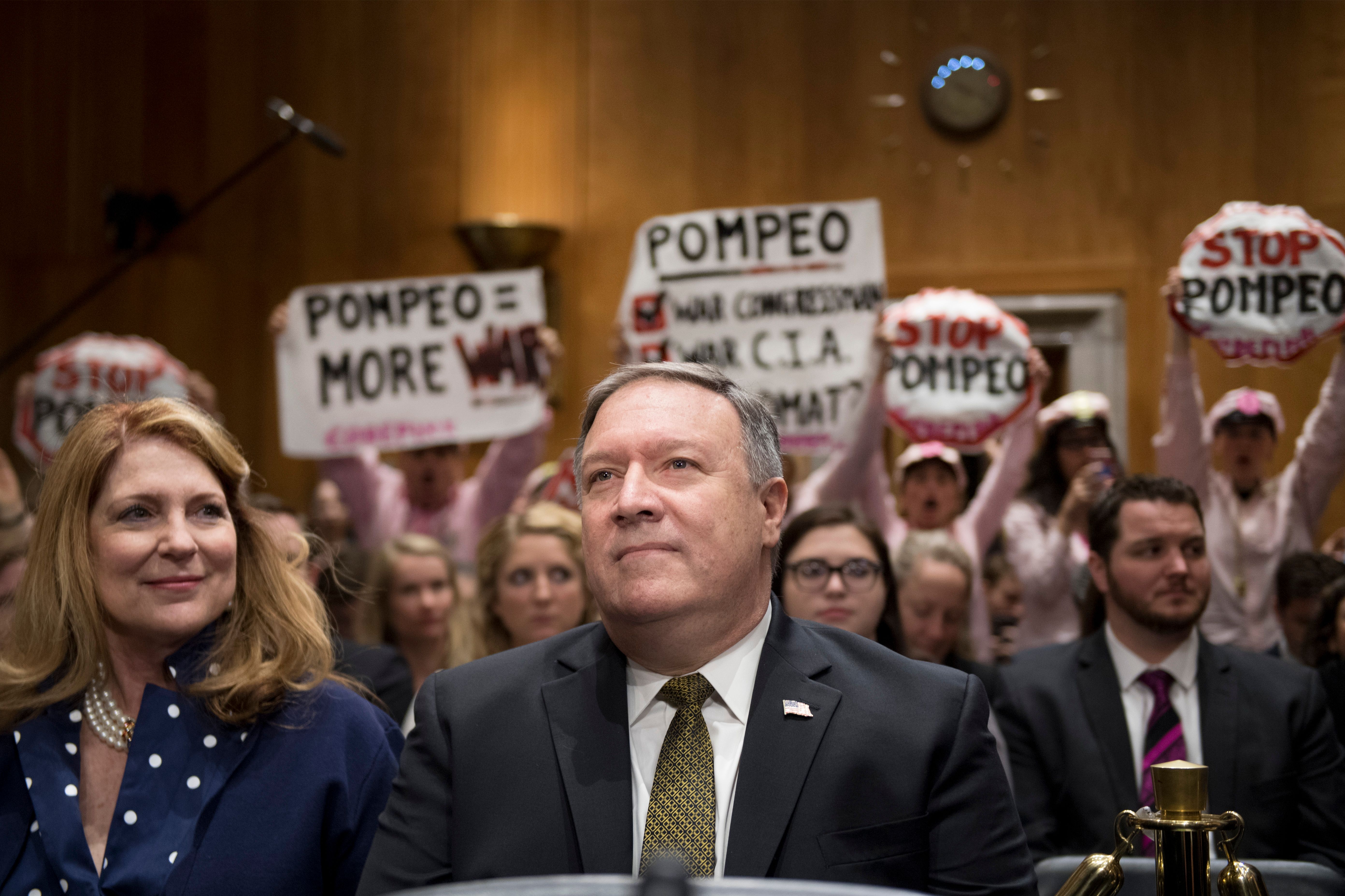 Protesters stand and chant with placards as US Secretary of State nominee Mike Pompeo arrives to testify before the Senate Foreign Relations Committee during his conformation hearing on Capitol Hill in Washington, DC, on April 12, 2018. (CREDIT: JIM WATSON/AFP/Getty Images)