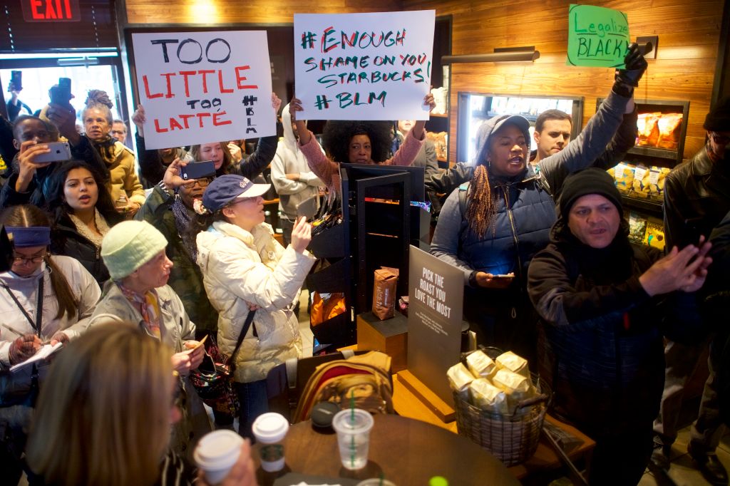 Protester Donn T (C) demonstrates inside a Center City Starbucks on April 15, 2018 in Philadelphia, Pennsylvania, after two black men were arrested there while waiting for a friend. CREDIT: Mark Makela/Getty Images
