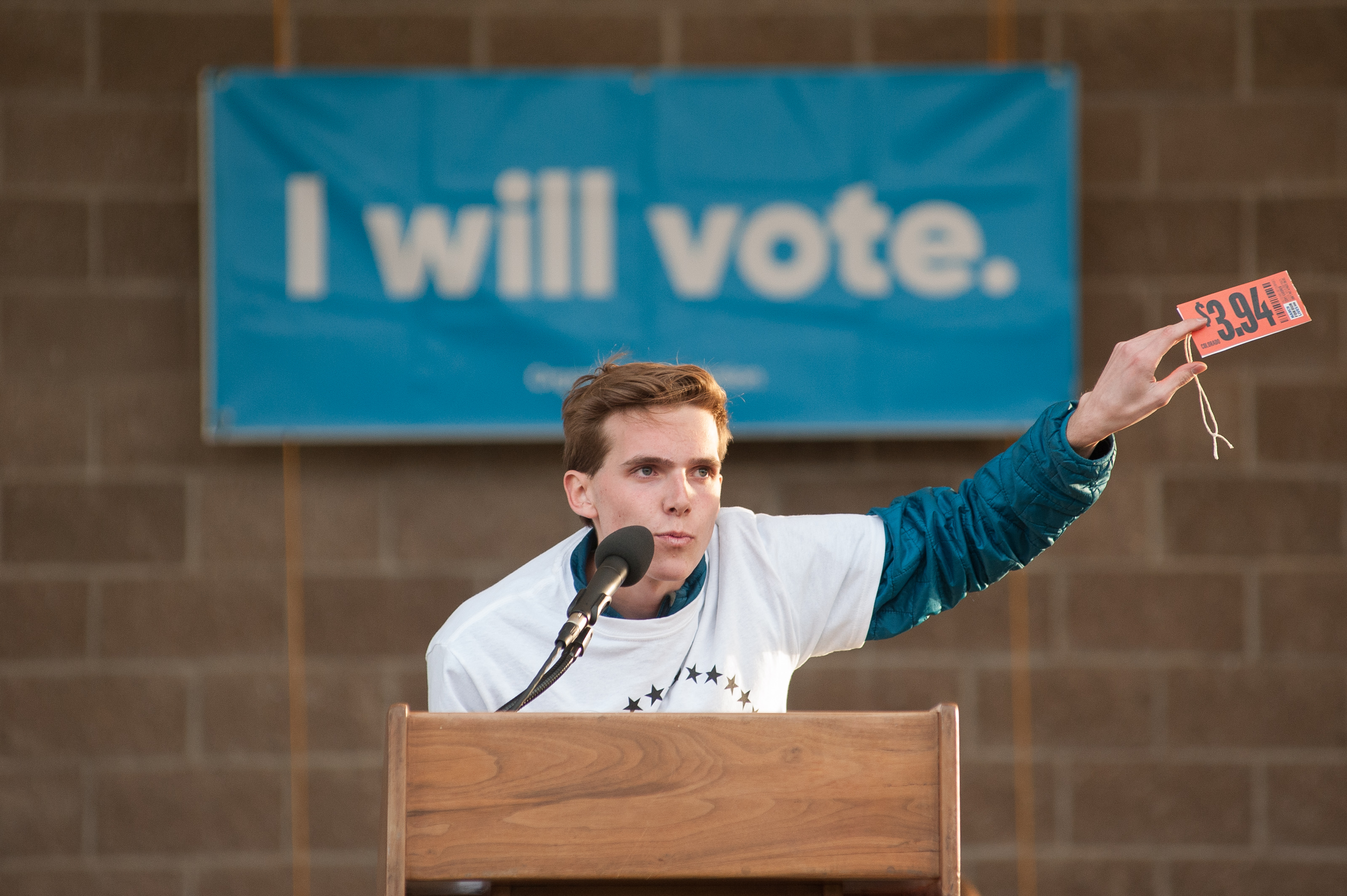 Sam Craig, a Chatfield High School student and co-director of Vote For Our Lives, holds up a sign reading $3.94 during a rally and vigil at Columbine High School on April 19, 2018 in Littleton, Colorado. (Credit: Theo Stroomer/Getty Images)