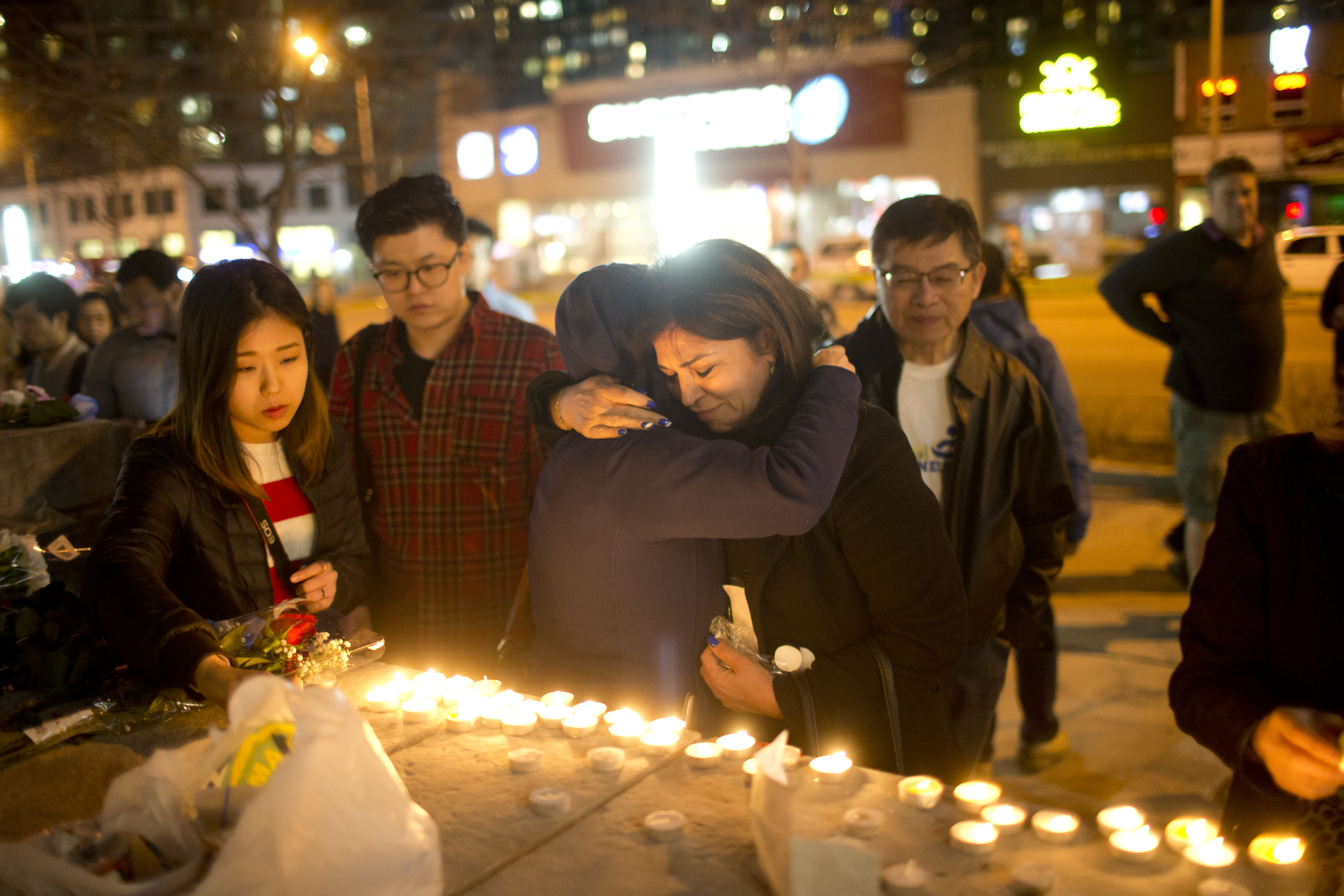 Passersby stop at a make-shift memorial set up on Yonge Street after Monday's tragedy where a man driving a cube van killed 10 pedestrians and injured another fifteen while traveling down the sidewalk. CREDIT: Lucas Oleniuk/Toronto Star/Getty Images.