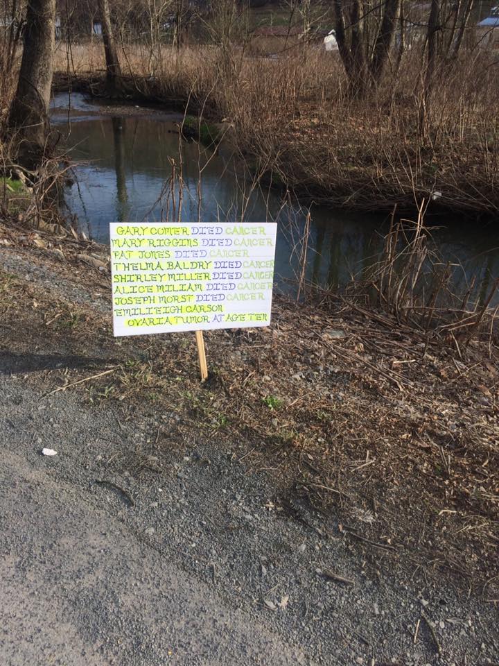 A sign next to Arbuckle Creek, which runs through the town of Minden, West Virginia, lists some of the people who are believed to have died from toxic contamination. CREDIT: MINDEN COMMUNITY ACTION TEAM, HEADWATERS DEFENSE