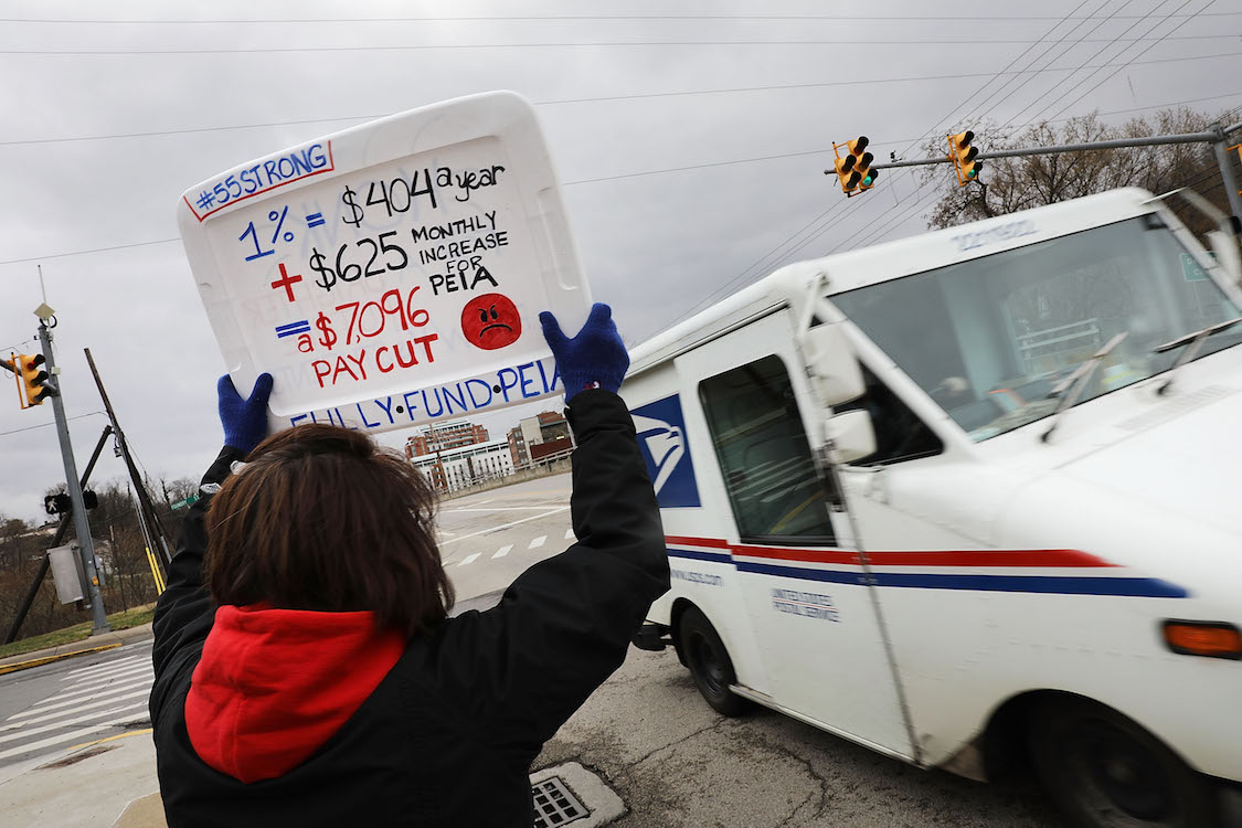 West Virginia teachers, students and supporters hold signs on a Morgantown street as they continue their strike on March 2, 2018 in Morgantown, West Virginia. (CREDIT: Spencer Platt/Getty Images)