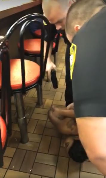 The moment where an officer brandishes a weapon -- though not his firearm -- at the woman. CREDIT: Screenshot/Facebook