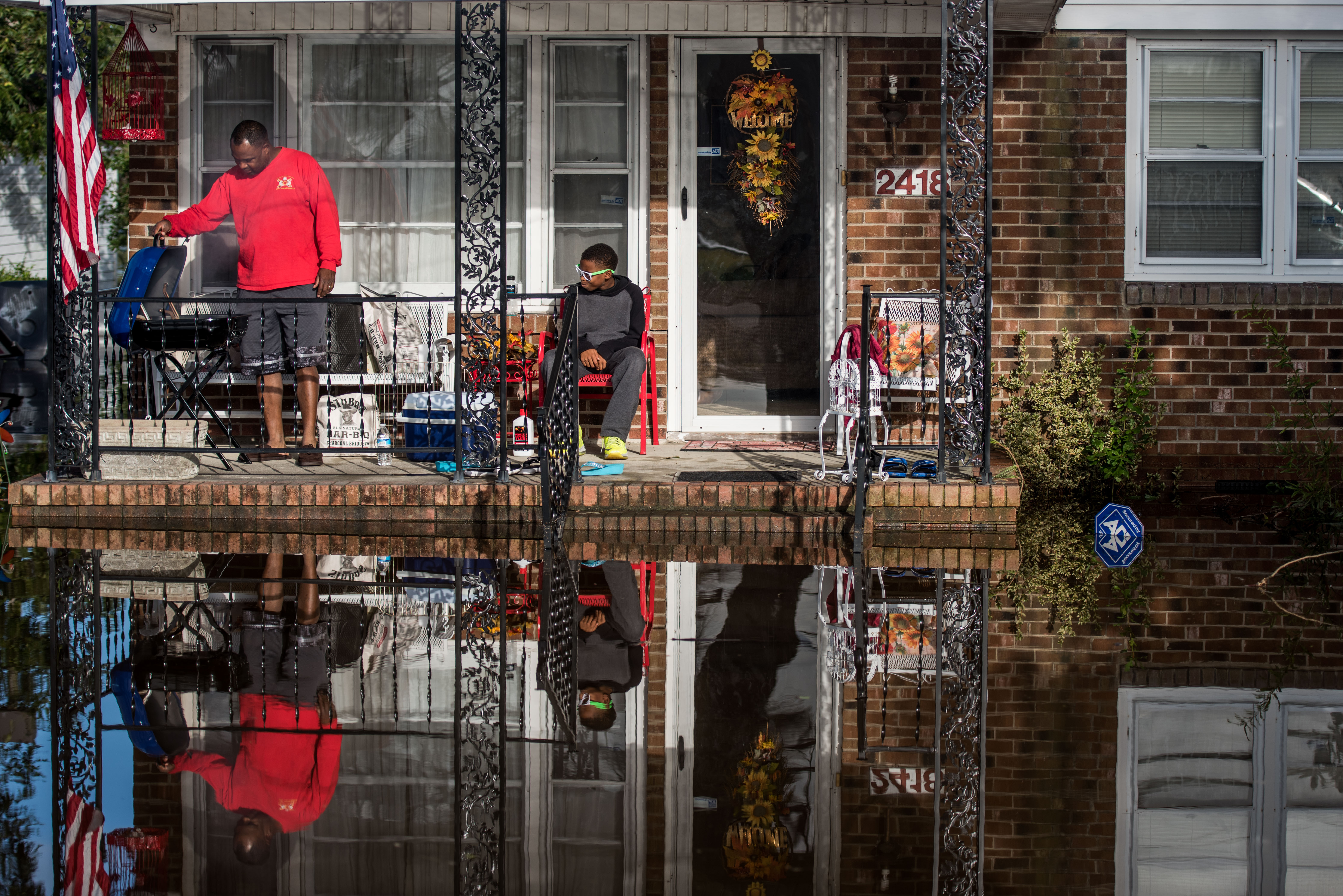 Robert Addison, left cooks on a charcoal grill with his son, Artis Addison, on October 12, 2016 in Lumberton, North Carolina, following flooding from Hurricane Matthew. (CREDIT: Sean Rayford/Getty Images)