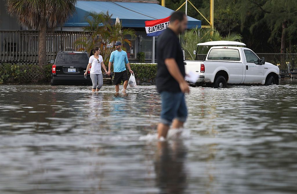 Yaneisy Duenas (L) and Ferando Sanudo walk through the flooded parking lot to their boat at the Haulover Marine Center on November 14, 2016 in North Miami, Florida. CREDIT: Joe Raedle/Getty Images