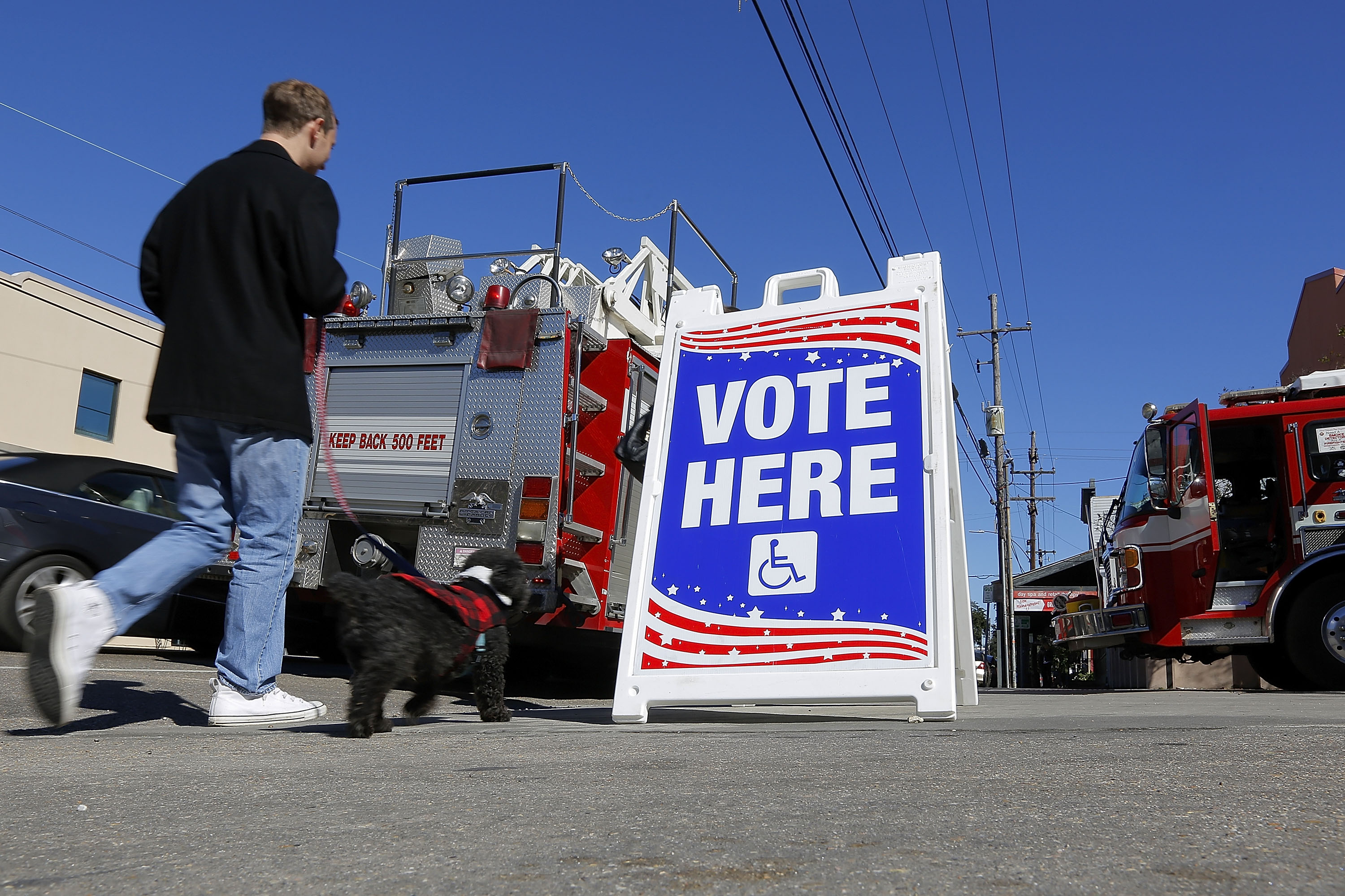 A man walks a dog past a polling station on December 10, 2016 in New Orleans, Louisiana. Photo by Jonathan Bachman/Getty Images
