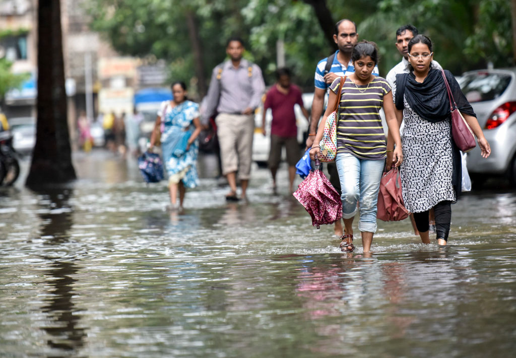 People walk through waterlogged street at Pratiksha Nagar, Sion on September 20, 2017 in Mumbai, India. CREDIT: Kunal Patil/Hindustan Times via Getty Images