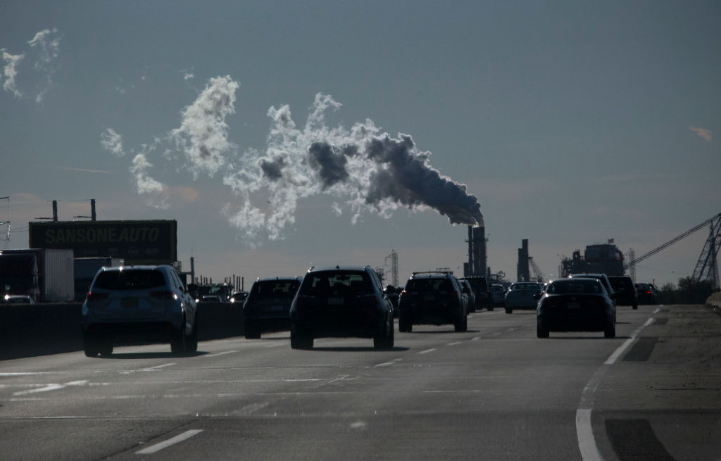 Vehicles move along the the New Jersey Turnpike while a factory emits smoke on November 17, 2017 in Carteret, New Jersey. CREDIT: Kena Betancur/VIEWpress/Corbis via Getty Images
