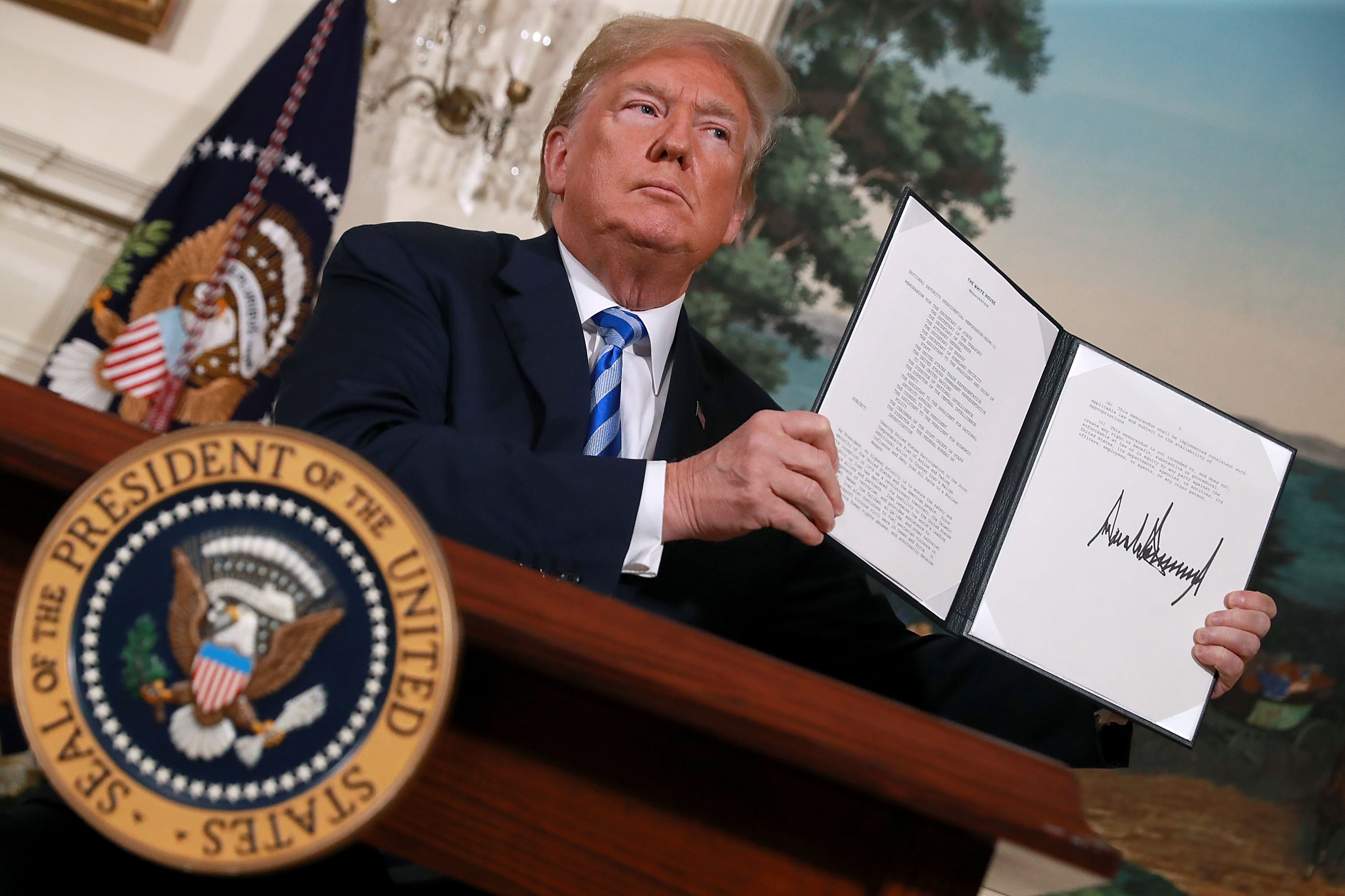 President Donald Trump holds up a memorandum that reinstates sanctions on Iran after he announced his decision to withdraw the United States from the 2015 Iran nuclear deal in the Diplomatic Room at the White House May 8, 2018 in Washington, DC. (Credit: Chip Somodevilla/Getty Images)