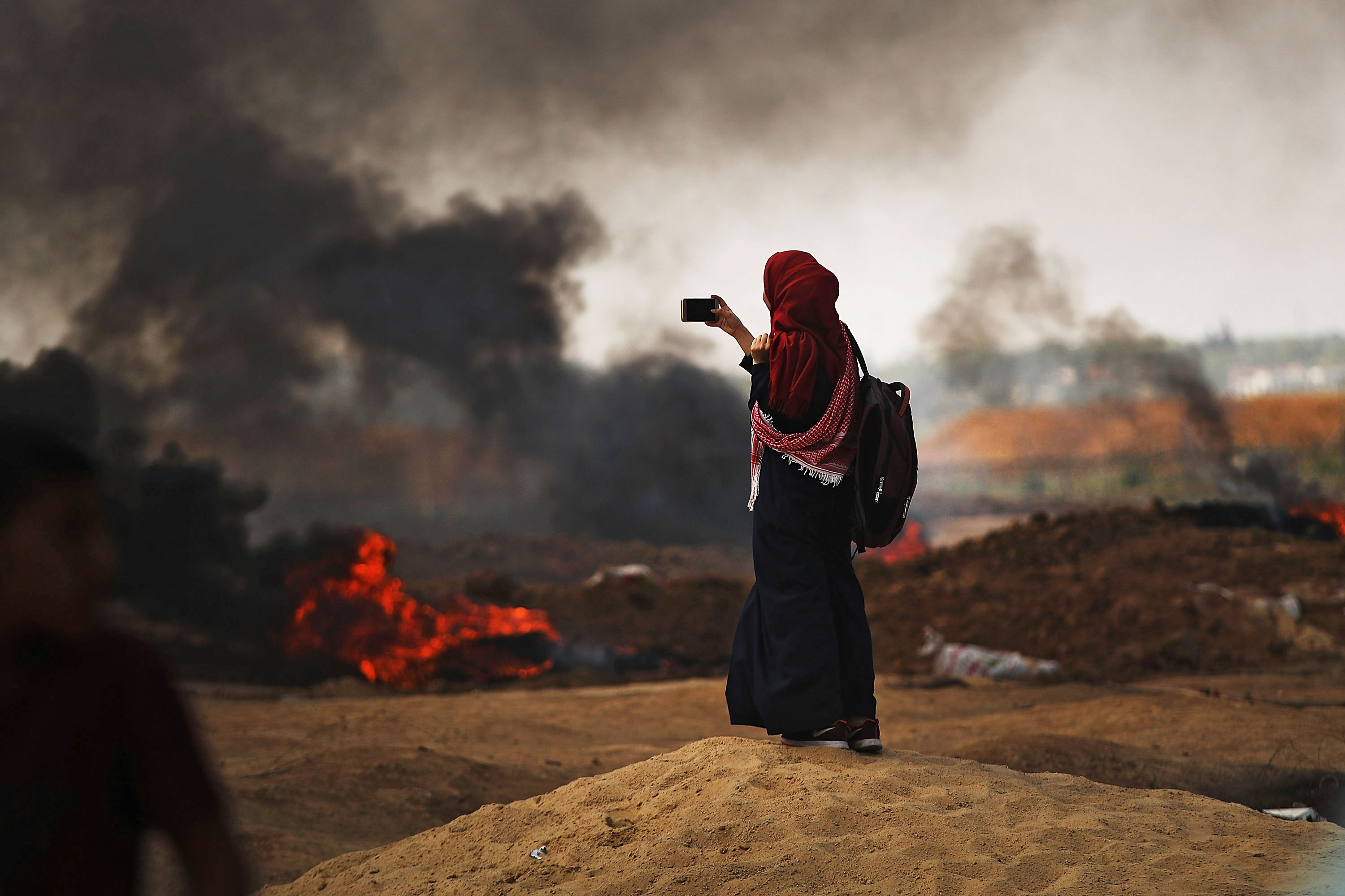 A Palestinian woman documents the situation at the border fence with Israel as mass demonstrations continue on May 14, 2018 in Gaza City. (CREDIT: Spencer Platt/Getty Images)