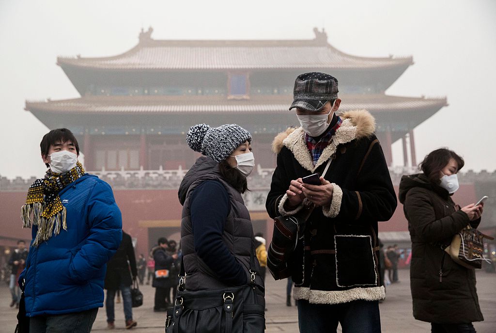 Chinese tourists wear masks as protection from the pollution outside the Forbidden City during a day of high pollution on in Beijing, China. CREDIT: Kevin Frayer/Getty Images