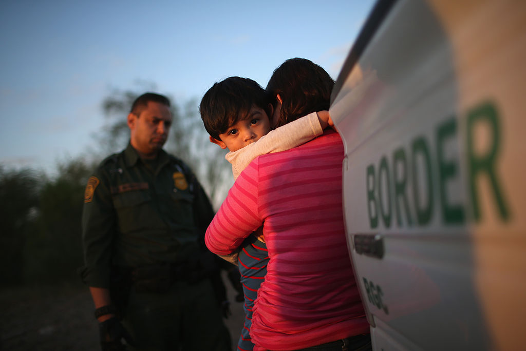A one-year-old from El Salvador clings to his mother after she turned themselves in to Border Patrol agents in Texas in 2015. CREDIT: John Moore/Getty Images