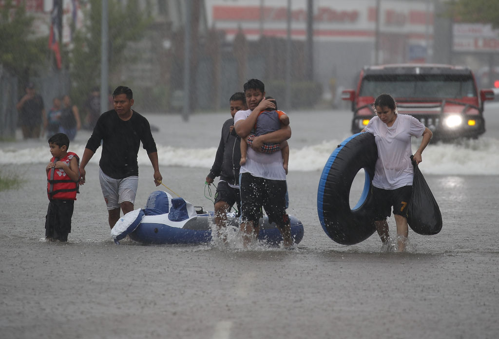 HOUSTON, TX - AUGUST 27: People walk down a flooded street as they evacuate their homes after the area was inundated with flooding from Hurricane Harvey on August 27, 2017 in Houston, Texas. CREDIT: Joe Raedle/Getty Images