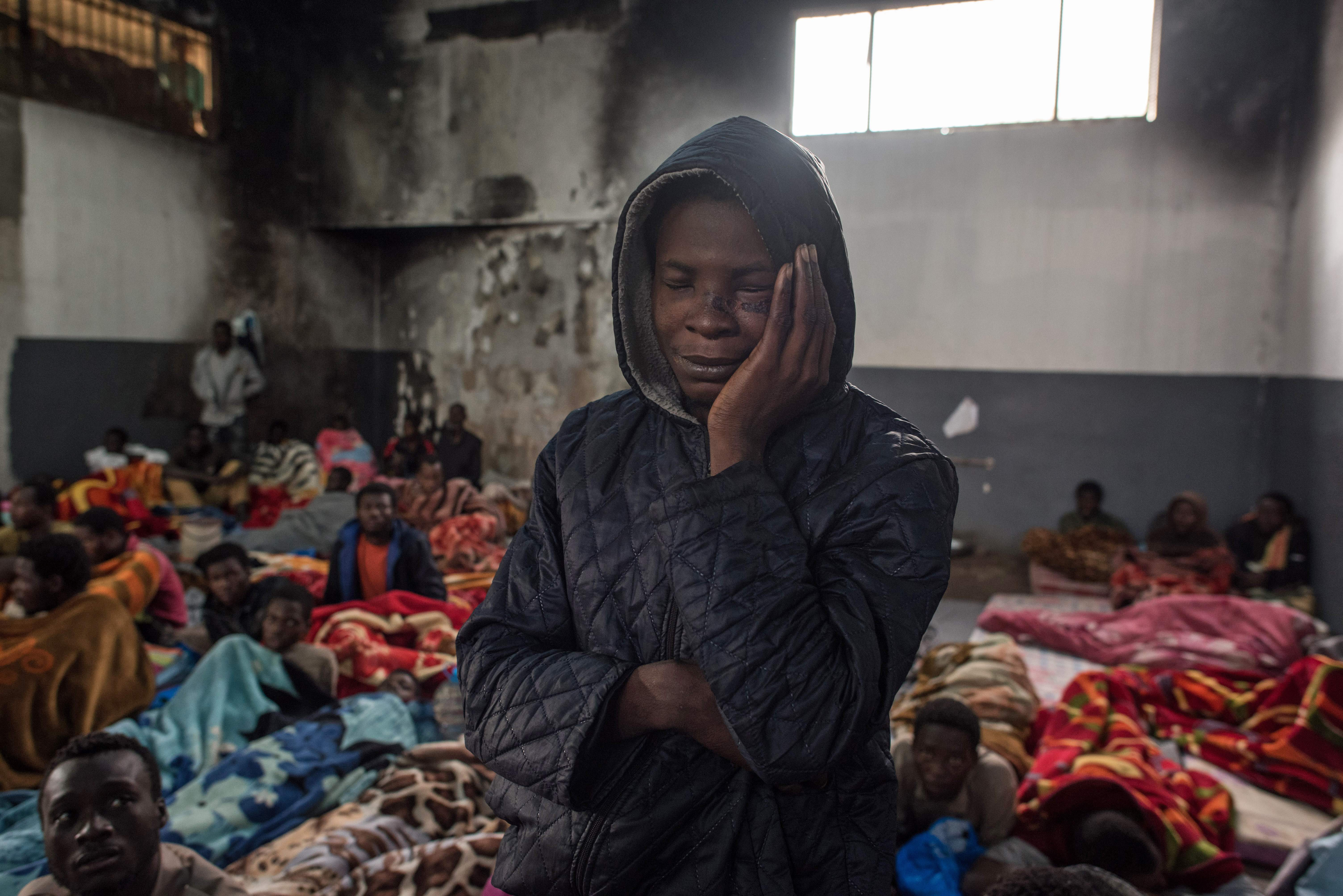 A migrant holds his head as he stands in a packed room at the Tariq Al-Matar detention centre on the outskirts of the Libyan capital Tripoli on November 27, 2017. CREDIT: Taha Jawashi/AFP/Getty Images.