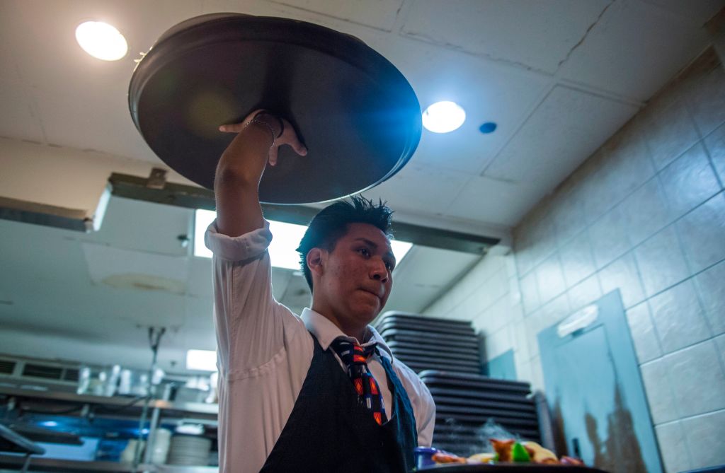A waiter carries food out of a kitchen in the Salvadoran and Latin American restaurant Lauriol Plaza in Washington, DC (ANDREW CABALLERO-REYNOLDS/AFP/Getty Images)
