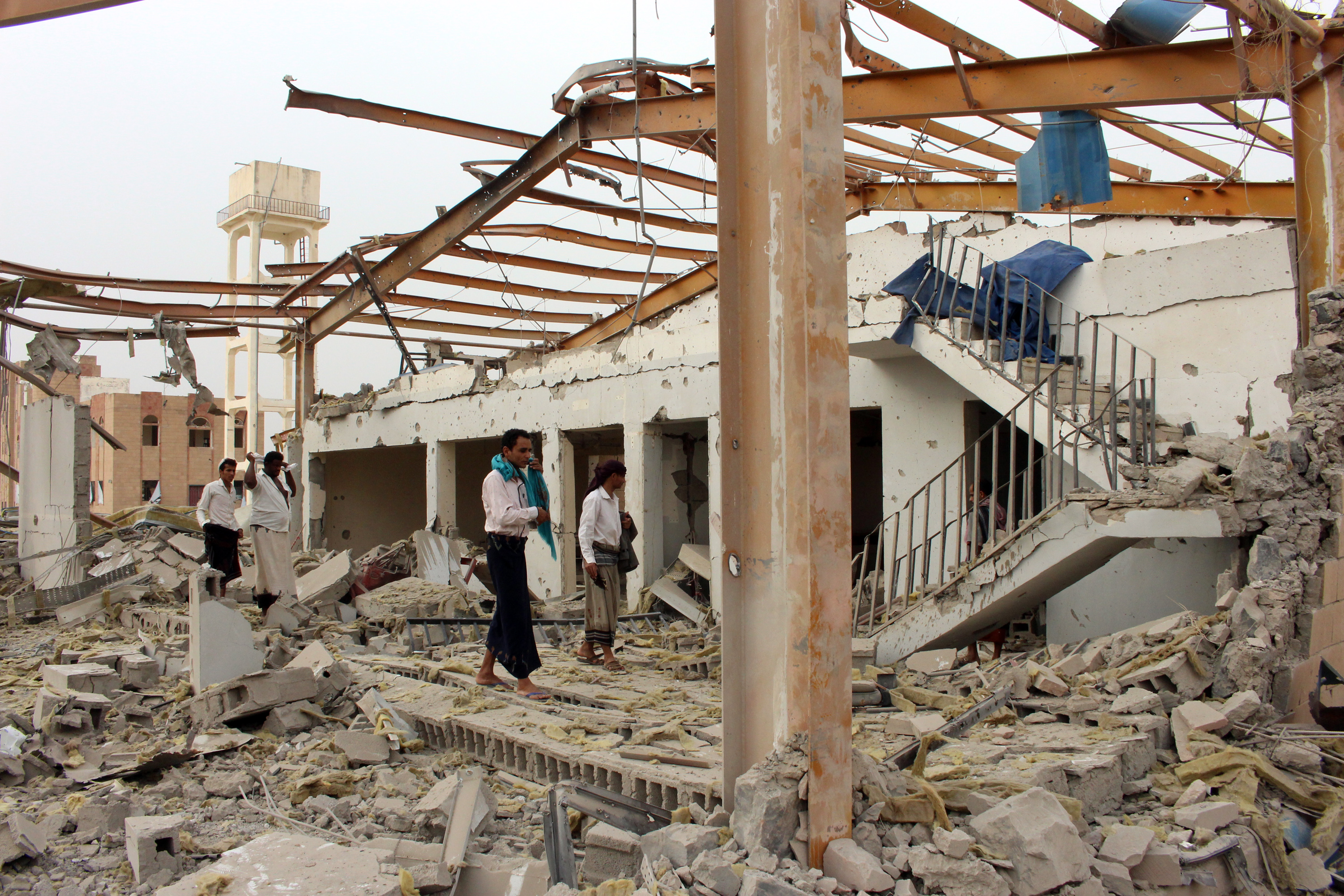 Yemeni men inspect the damage caused by a Saudi-led air strike on a cholera treatment center. (CREDIT: Essa Ahmed/AFP/Getty Images)