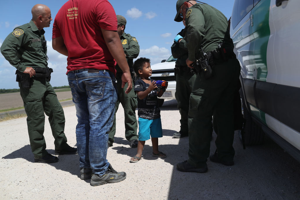 A boy holds a toy truck up to Border Patrol agents as they detain him with his father near the U.S.-Mexico border in Mission, TX, on June 12. CREDIT: John Moore/Getty Images