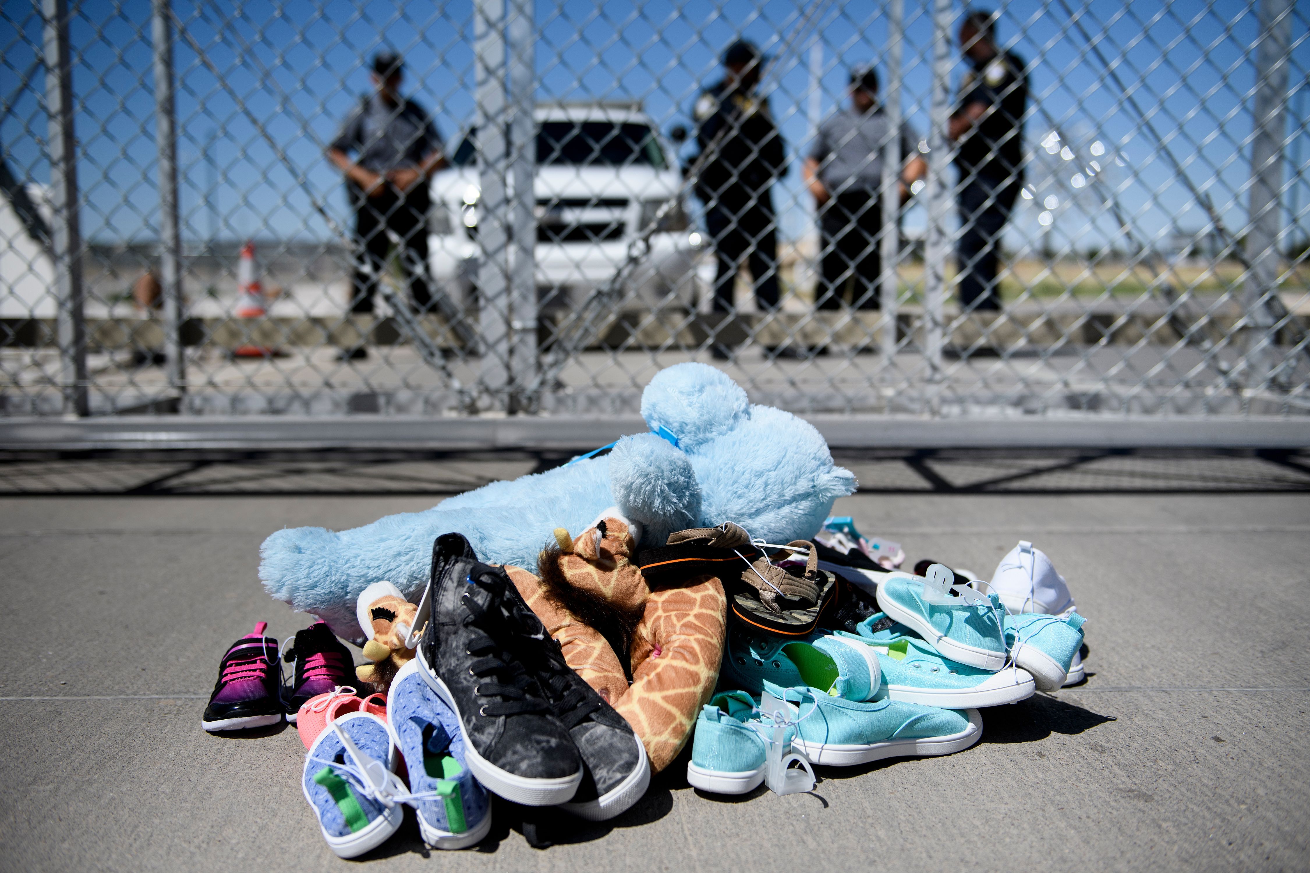 Security personal stand before shoes and toys left at the Tornillo Port of Entry where minors crossing the border without proper papers have been housed after being separated from adults, (CREDIT: BRENDAN SMIALOWSKI/AFP/Getty Images)