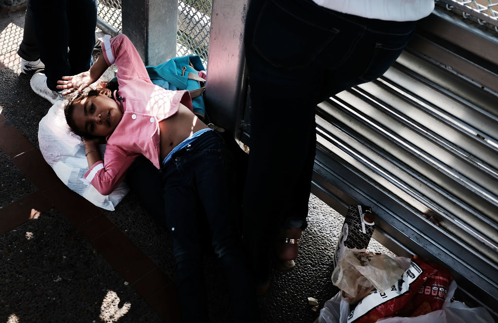 A Honduran girl, fleeing poverty and violence in her home country, waits with her mother along the border bridge. (Photo by Spencer Platt/Getty Images)