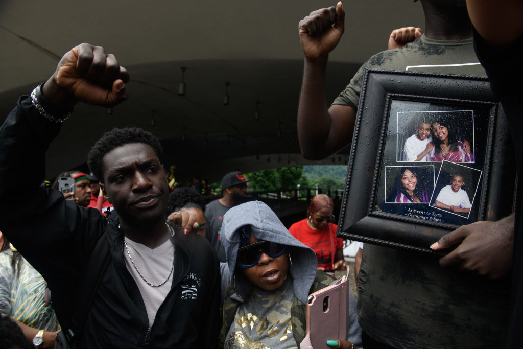 A man holds photos of Antwon Rose Jr. during a protest over Officer Michael Rosfeld's killing of the teenager in mid-June in East Pittsburgh. CREDIT: Justin Merriman/Getty Images