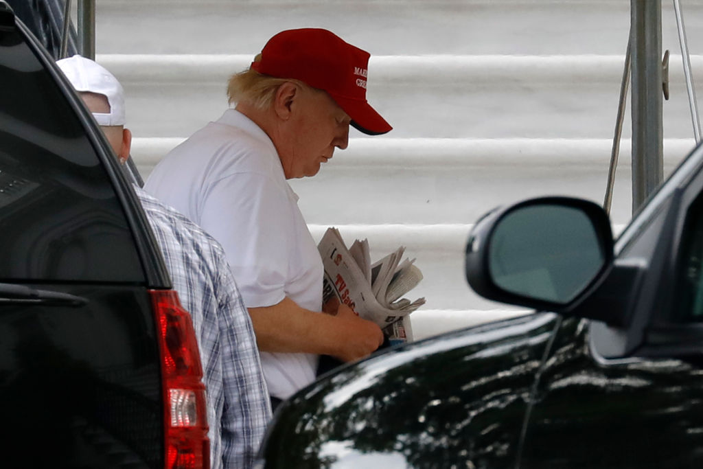 US President Donald Trump holds newspapers as he returns to the White House in Washington from Trump National Golf Club on Sunday. (CREDIT: Photo by YURI GRIPAS / AFP)
