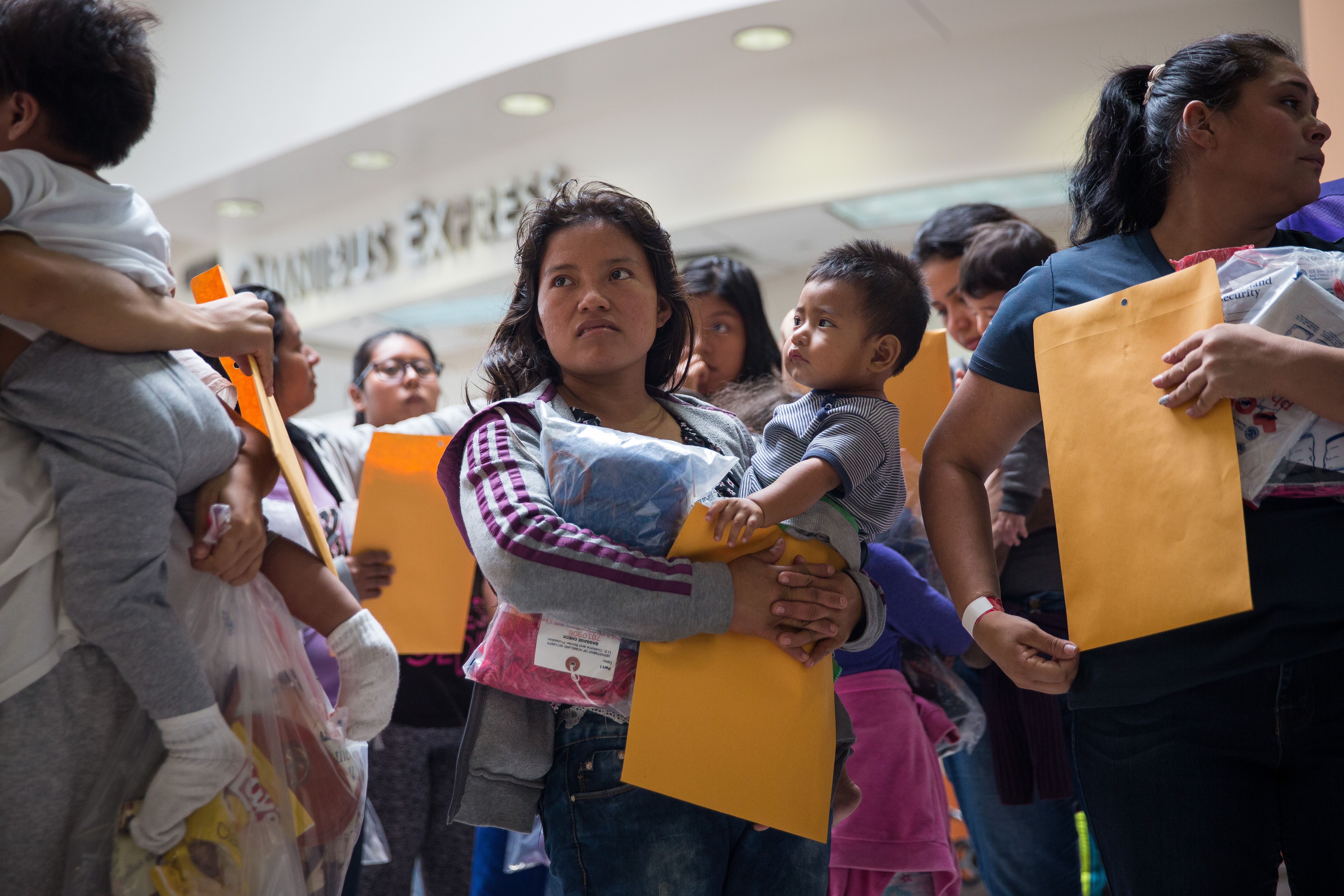 Immigrants wait to head to a nearby relief center shortly after release from detention through "catch and release" immigration policy on June 17, 2018 in McAllen, Texas. "Catch and release" is a protocol under which people detained by US authorities as unlawful immigrants can be released while they wait for a hearing. (Credit: Loren ELLIOTT / AFP)