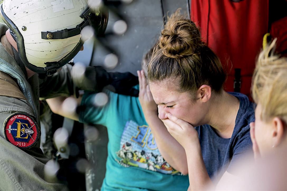 Navy Petty Officer 2nd Class Jansen Schamp reassures civilians rescued from Pine Forest Elementary School in Vidor, Texas on August 31, 2017. Pine Forest had served as a shelter for victims of Hurricane Harvey until floodwaters reached the school. Scientists say that climate change made the storm measurably worse. CREDIT: Petty Officer 1st Class Christopher Lindahl, United States Navy
