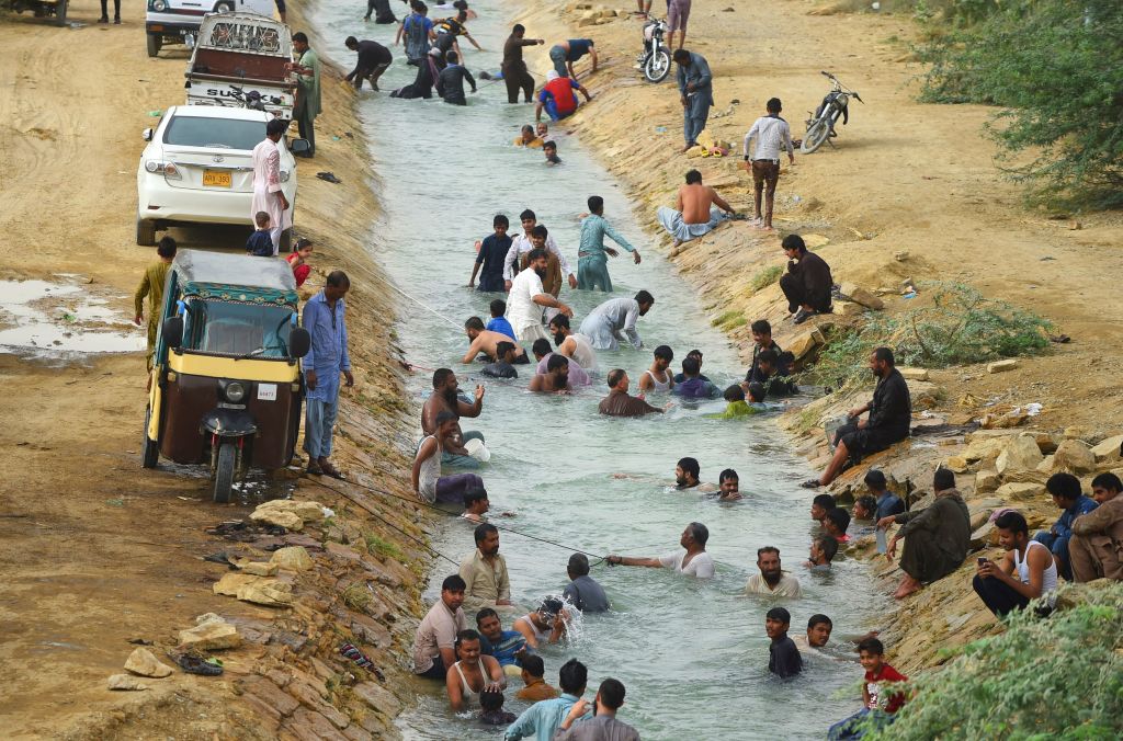 Pakistani residents cool off at a canal during heatwave as temperatures reach 44 degrees Celsius (111 Fahrenheit) in Karachi on May 30, 2018. CREDIT: RIZWAN TABASSUM / AFP