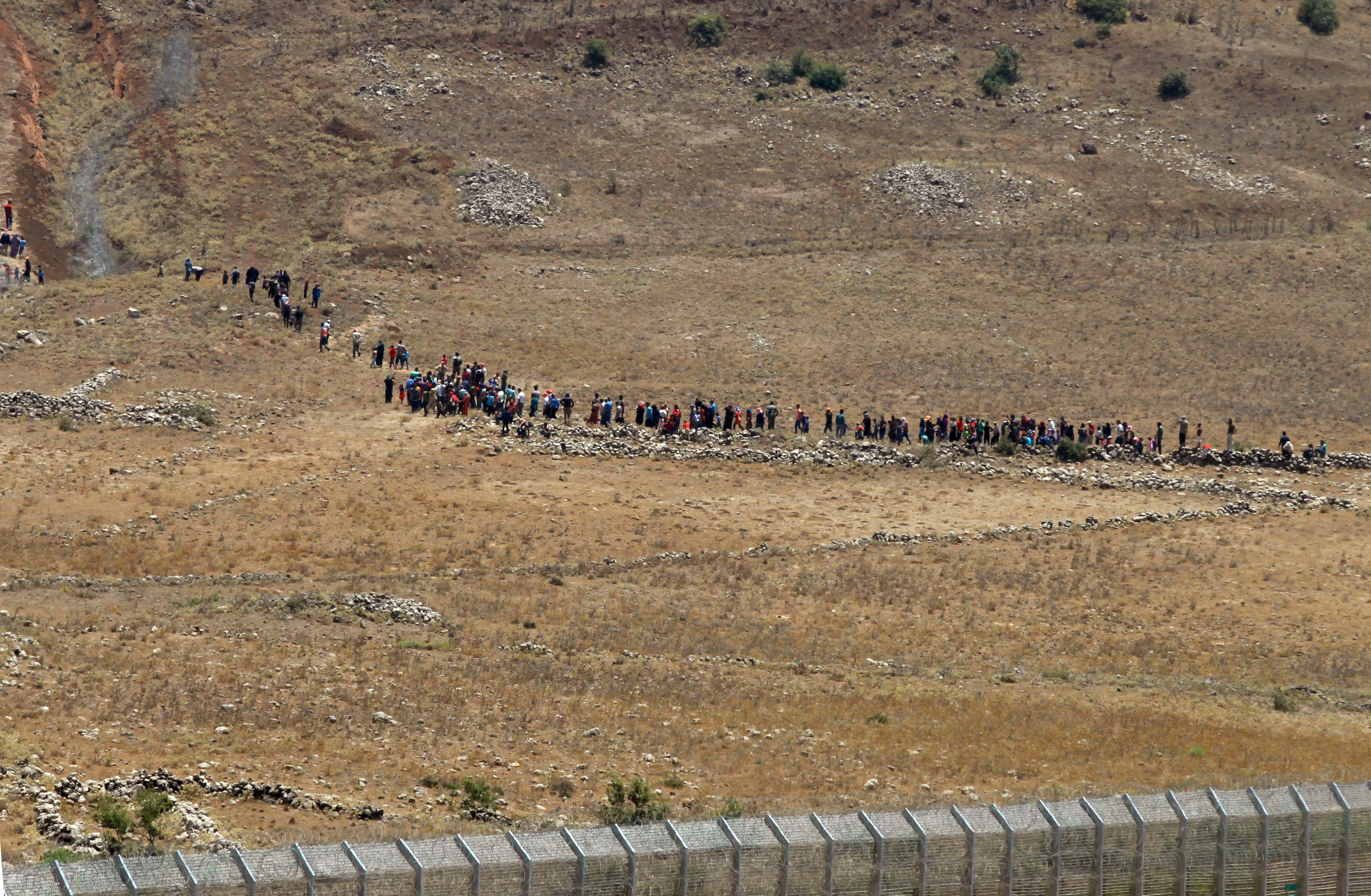 Having been denied refuge, displaced Syrians are turned back from the Golan Heights fence and returning to their camp near the Syrian village of Burayqah in the southern province of Quneitra on Tuesday, July 17, 2018. CREDIT: Jalaa Marey/AFP/Getty Images.