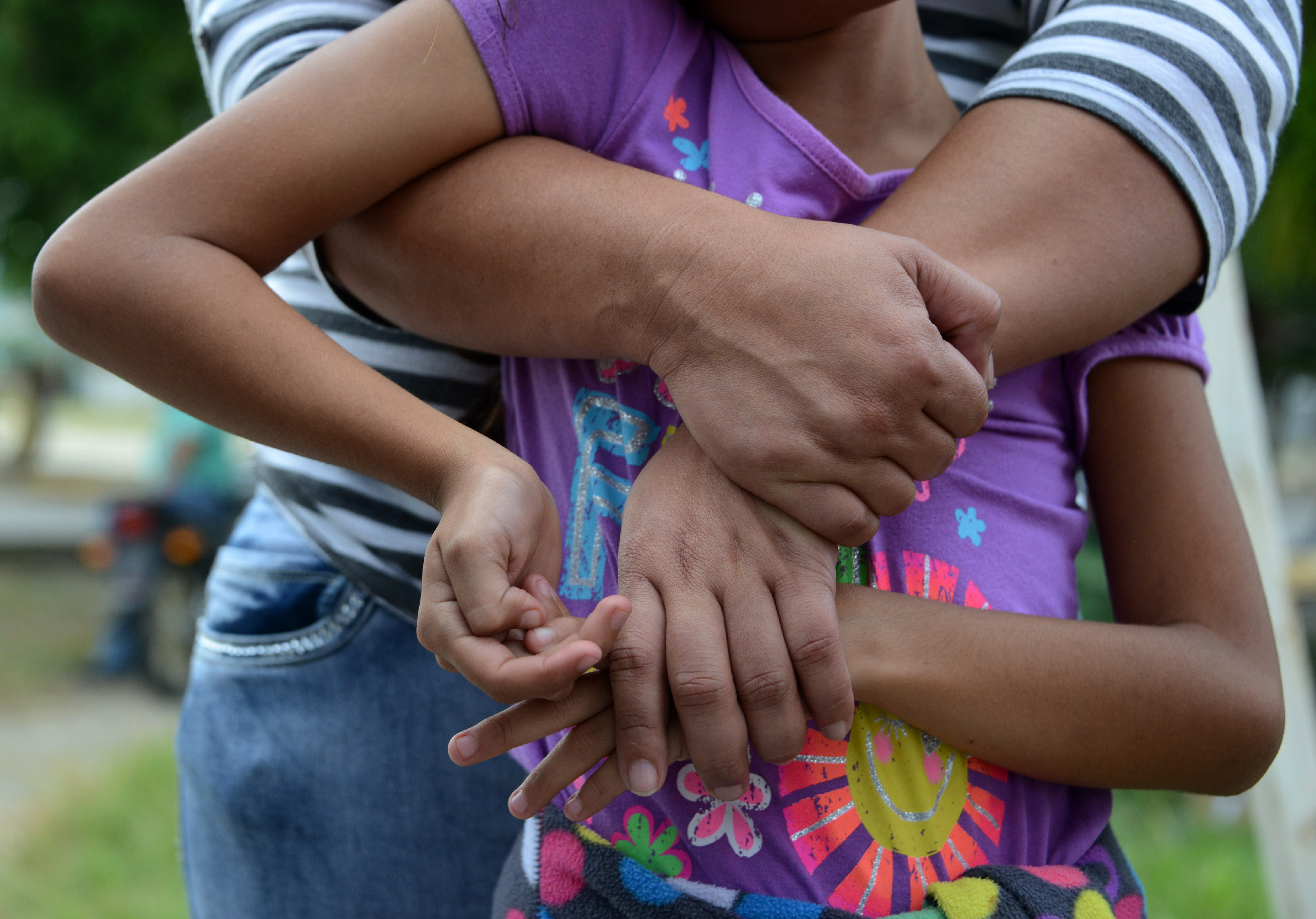 A woman holds her daughter tight as she speaks to the press upon arriving in San Pedro Sula (Orlando Sierra/AFP/Getty Images)