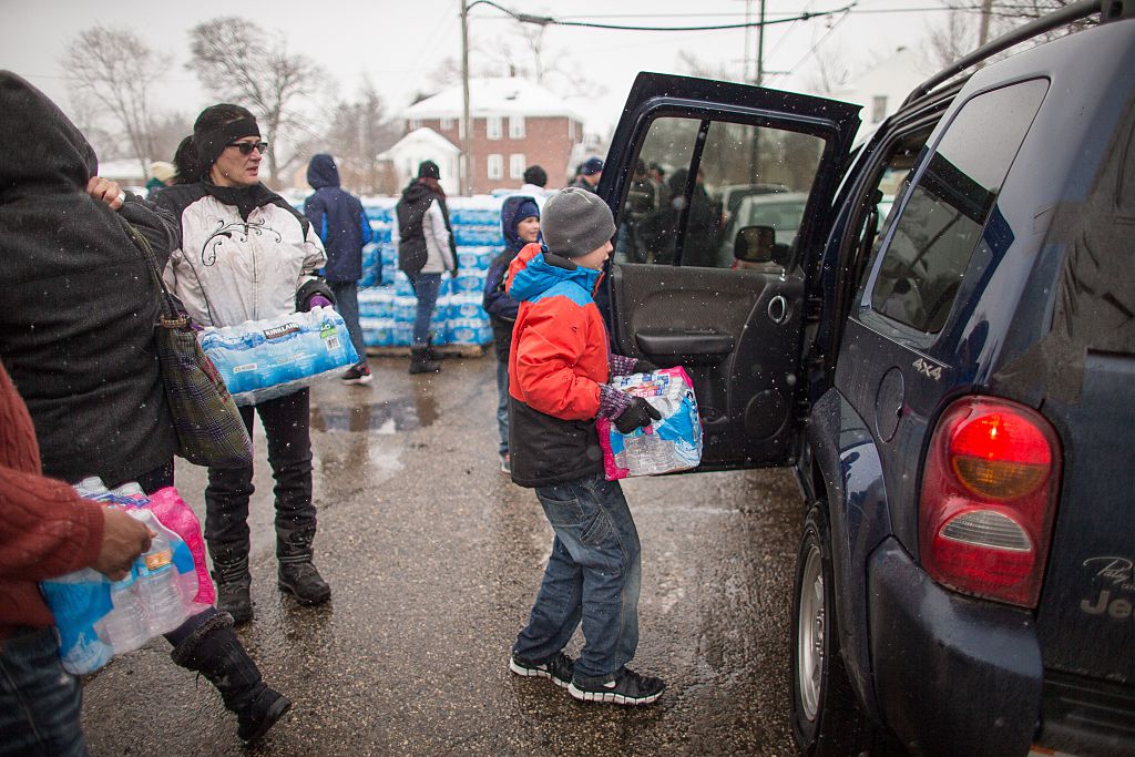Volunteers load cases of free water into waiting vehicles at a water distribution centre at Salem Lutheran Church in Flint, Michigan, on March 5, 2016. CREDIT: GEOFF ROBINS/AFP/Getty Images