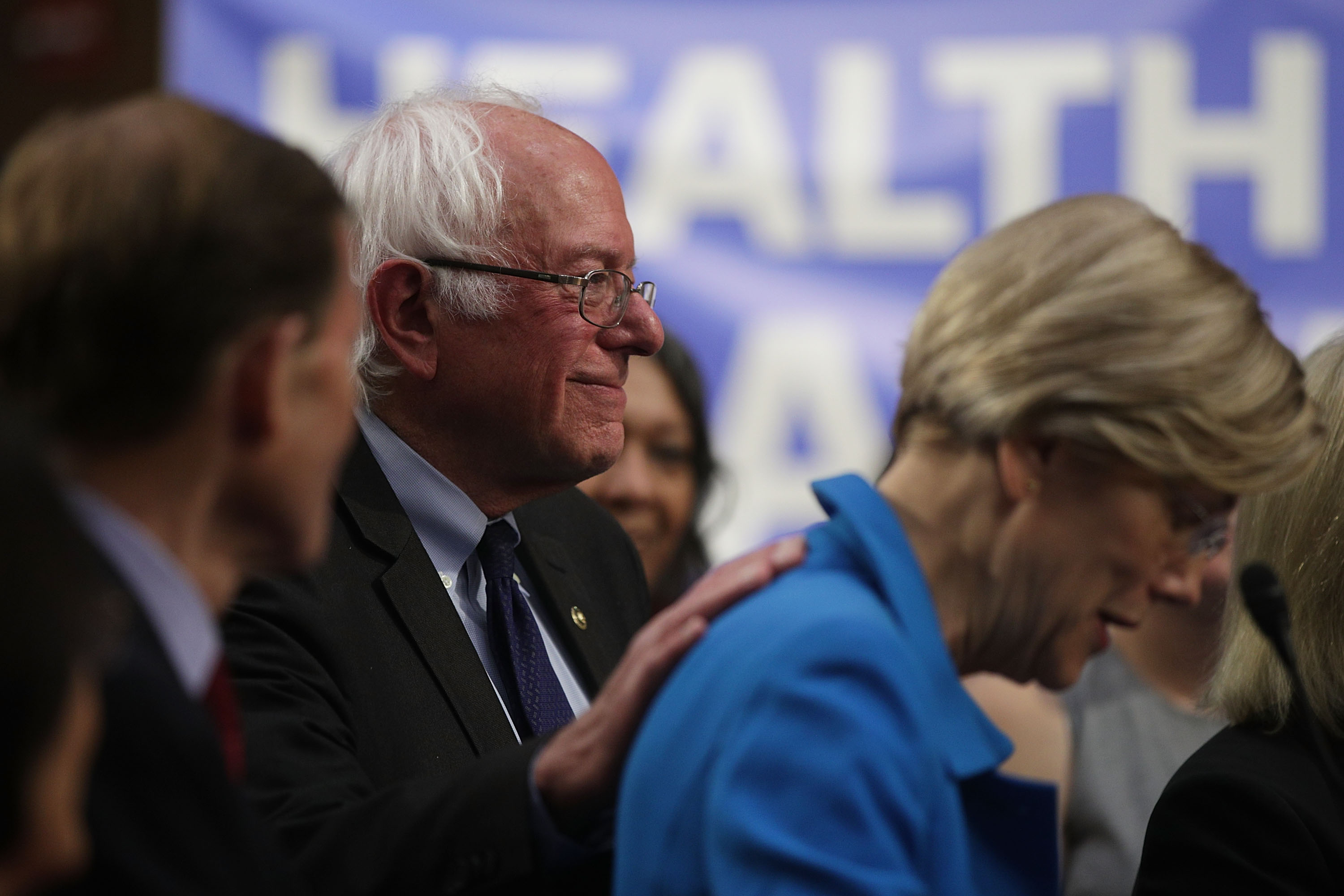 U.S. Sen. Bernie Sanders (I-VT) (2nd L) pats on the back of Sen. Elizabeth Warren (D-MA) (R) during an event on health care September 13, 2017 on Capitol Hill in Washington, DC. CREDIT: Alex Wong/Getty Images