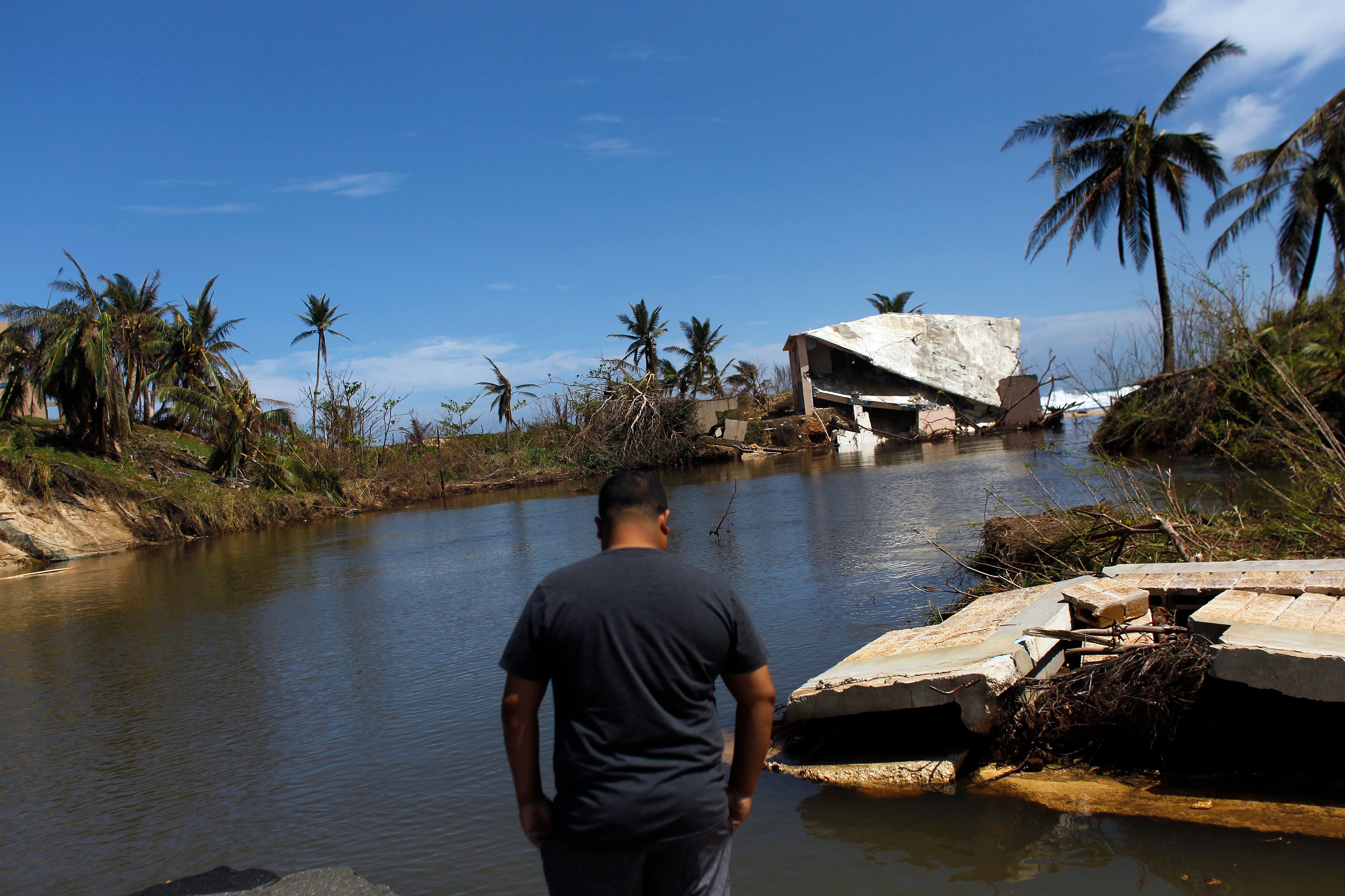 A man surveys a house that was washed away by heavy surf during the passing of Hurricane Maria in Manati, Puerto Rico on October 6, 2017. / AFP PHOTO / Ricardo ARDUENGO (Photo credit should read RICARDO ARDUENGO/AFP/Getty Images)