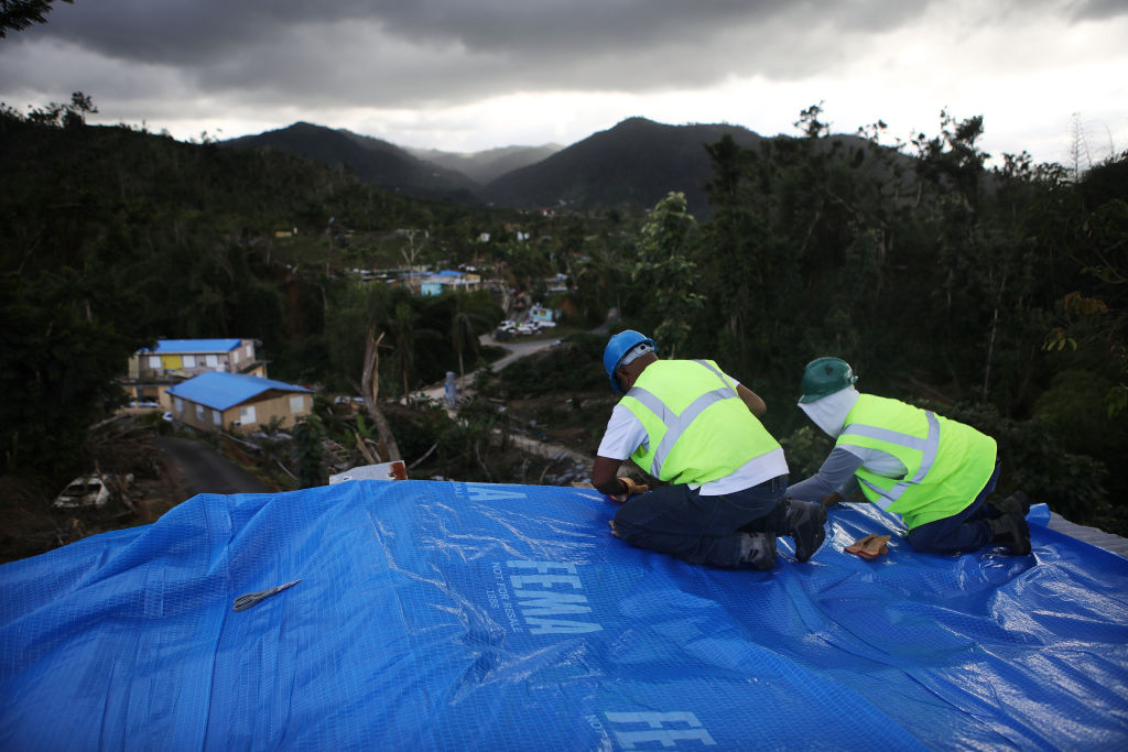 Contractors apply a FEMA tarp to a home damaged by Hurricane Maria and without electricity on December 20, 2017 in Morovis, Puerto Rico. CREDIT: Mario Tama/Getty Images