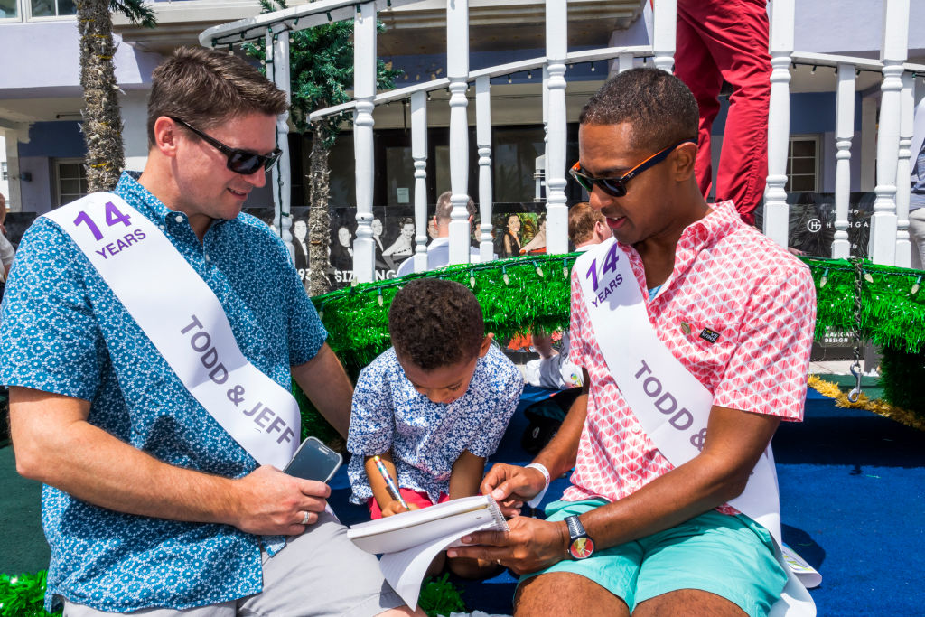 A same-sex couple enjoying 2017's Miami Beach Pride Festival with their child. CREDIT: Jeffrey Greenberg/UIG via Getty Images