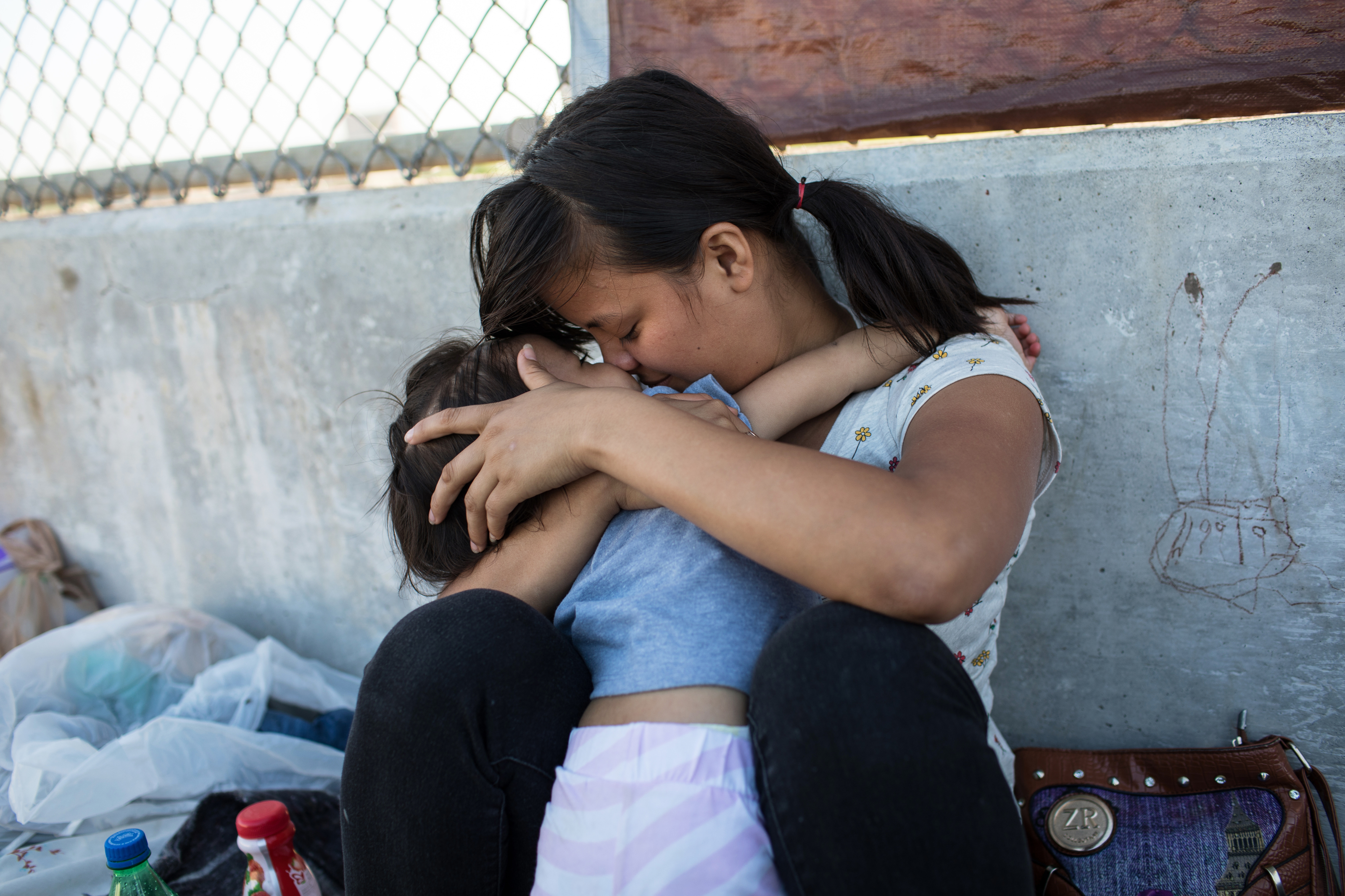 A Honduran woman embraces her 2-year-old daughter as they wait on the Mexican side of the Brownsville & Matamoros International Bridge after being denied entry into the U.S., on June 28, 2018 near Brownsville, Texas. (Credit: Tamir Kalifa/Getty Images)
