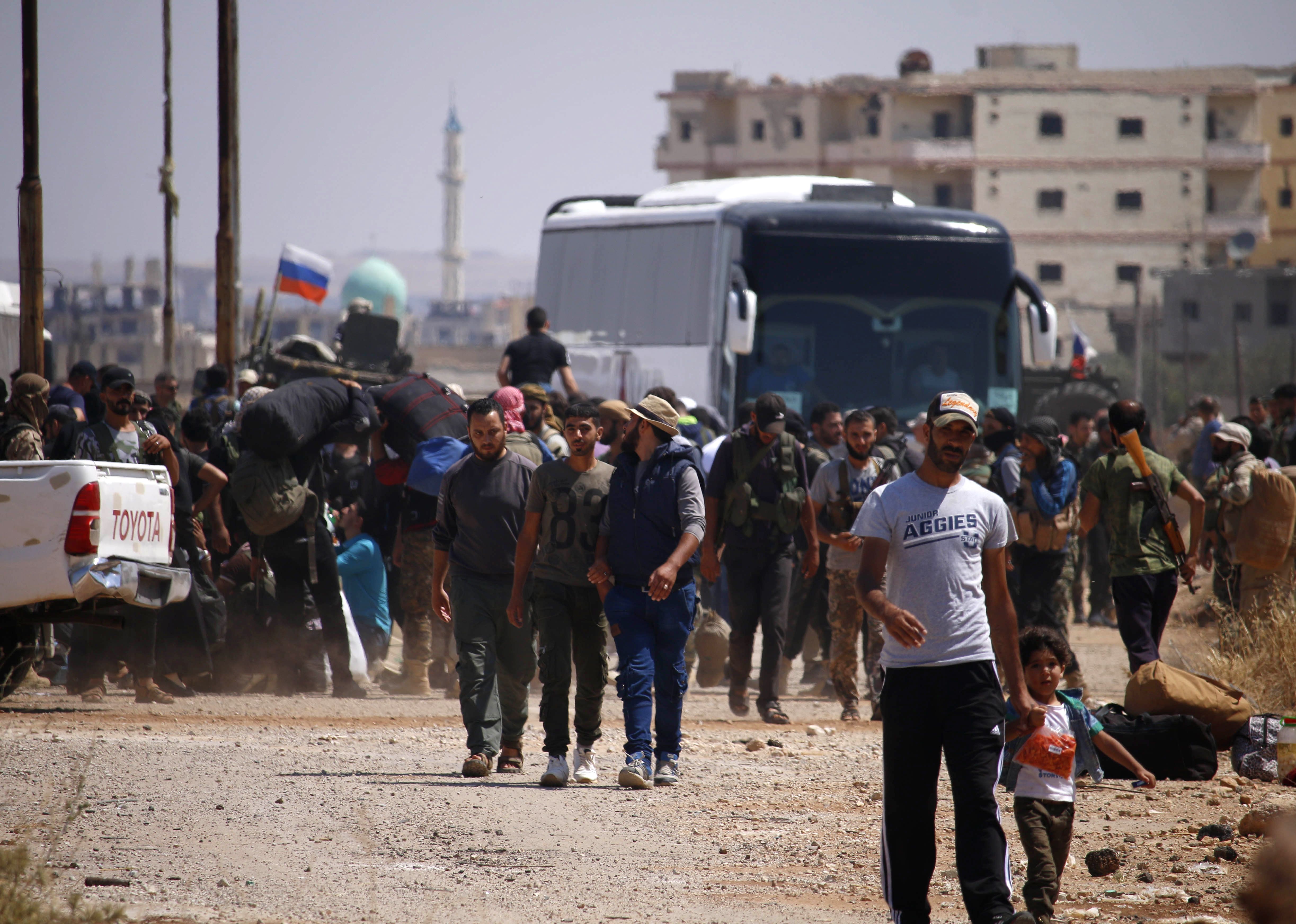 Syrian rebels and their families stand by buses to be evacuated from Daraa city, on July 15, 2018. CREDIT: Mohamad Abazeed/AFP/Getty Images.
