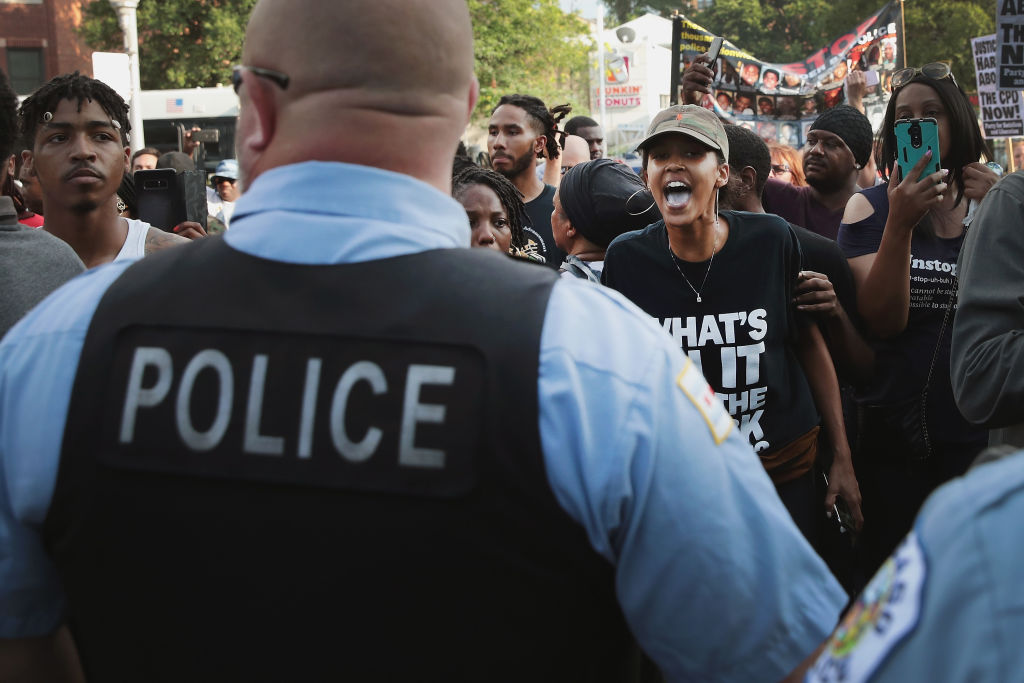 Police and protesters faced off through the evening hours on Saturday at the intersection where officers shot and killed Harith Augustus, a local barber. Police quickly released one short snippet of video, but it leaves much unanswered about officers' handling of Augustus, who had a licensed firearm on his hip when officers approached. CREDIT: Scott Olson/Getty Images