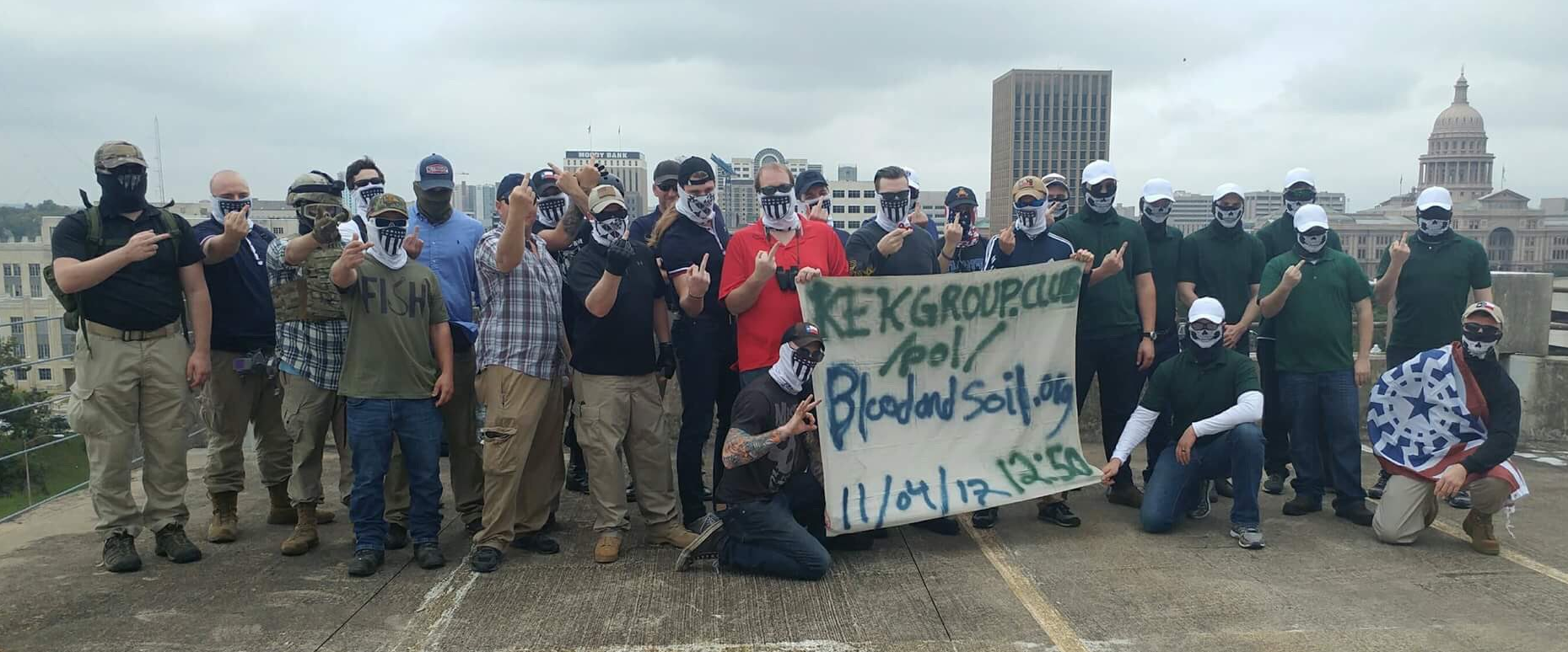 "Screwston Antifa" said Jones is pictured here with a group holding a sign advocating a white supremacist, anti-Semitic organization.