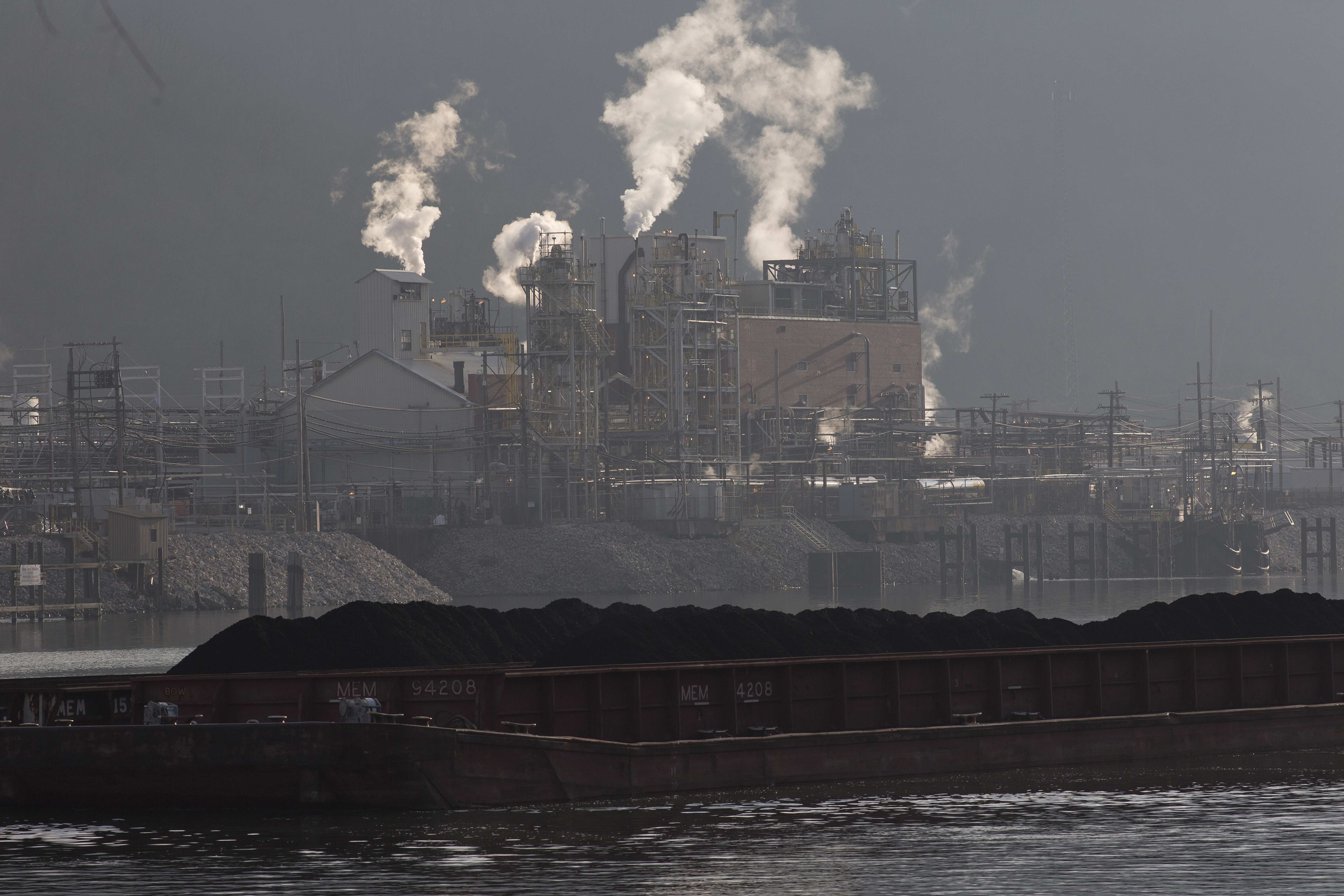 South of Charleston, West Virginia, a coal barge travels up the Kanawha River, passing the Dupont chemical plant. CREDIT: Andrew Lichtenstein/Corbis via Getty Images