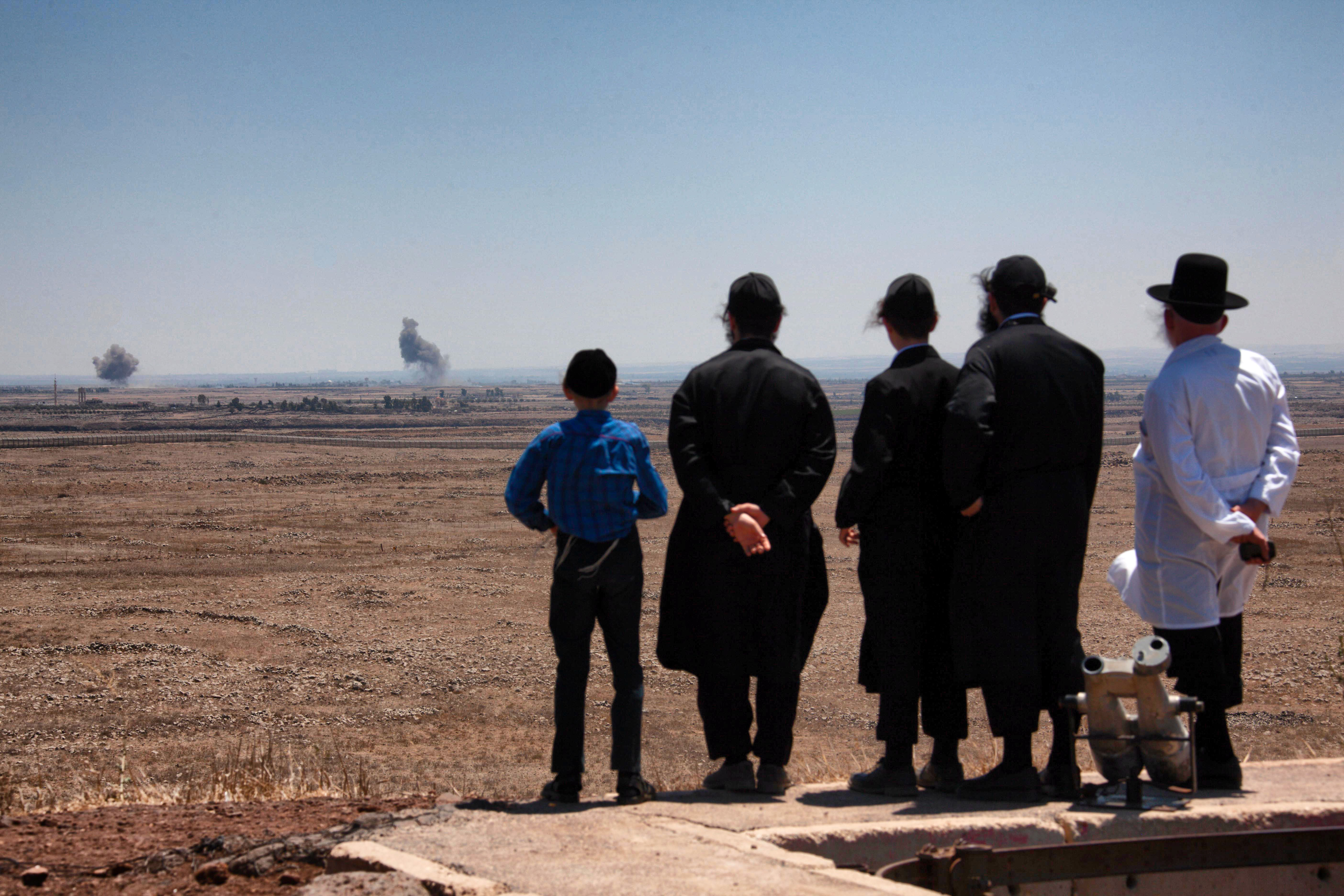 Israeli civilians on the Golan Heights watch as fighting rages just beyond the border fence in Syria between Syrian government forces and ISIS fighters, on Friday, 27 July 2018. CREDIT: Mati Milstein/NurPhoto/Getty Images.
