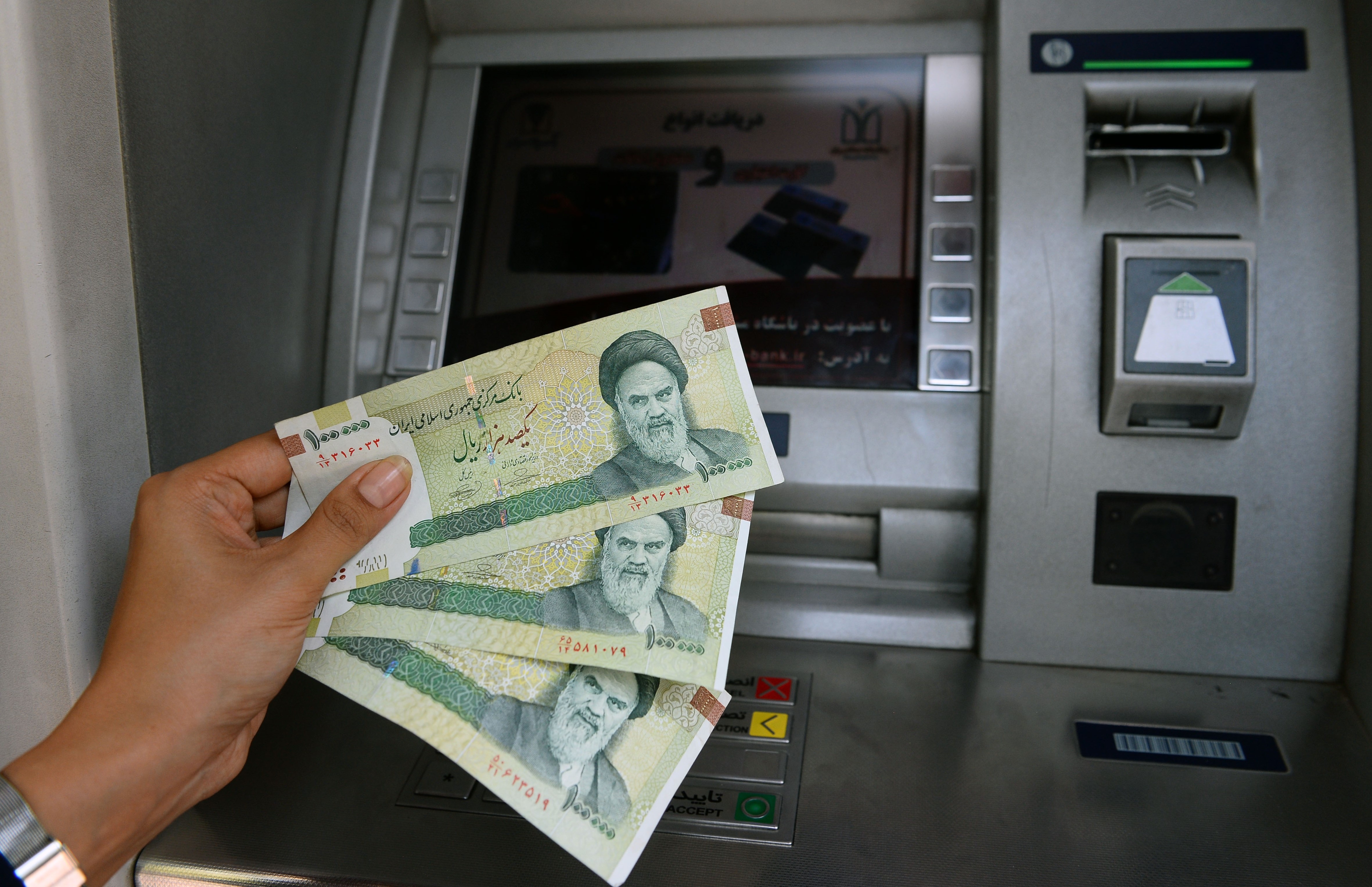 A woman holds Iranian currency near an ATM as the riyal devaluated to its lowest value against the US dollar last week besides the U.S. will enforce sanctions against Iran on Monday, in Tehran, Iran on August 06, 2018. The sudden increase in the exchange rates causes lowering the purchasing power, shut down of business offices and increase the unemployment rate sharply in recent days. CREDIT: Fatemeh Bahrami/Anadolu Agency/Getty Images.