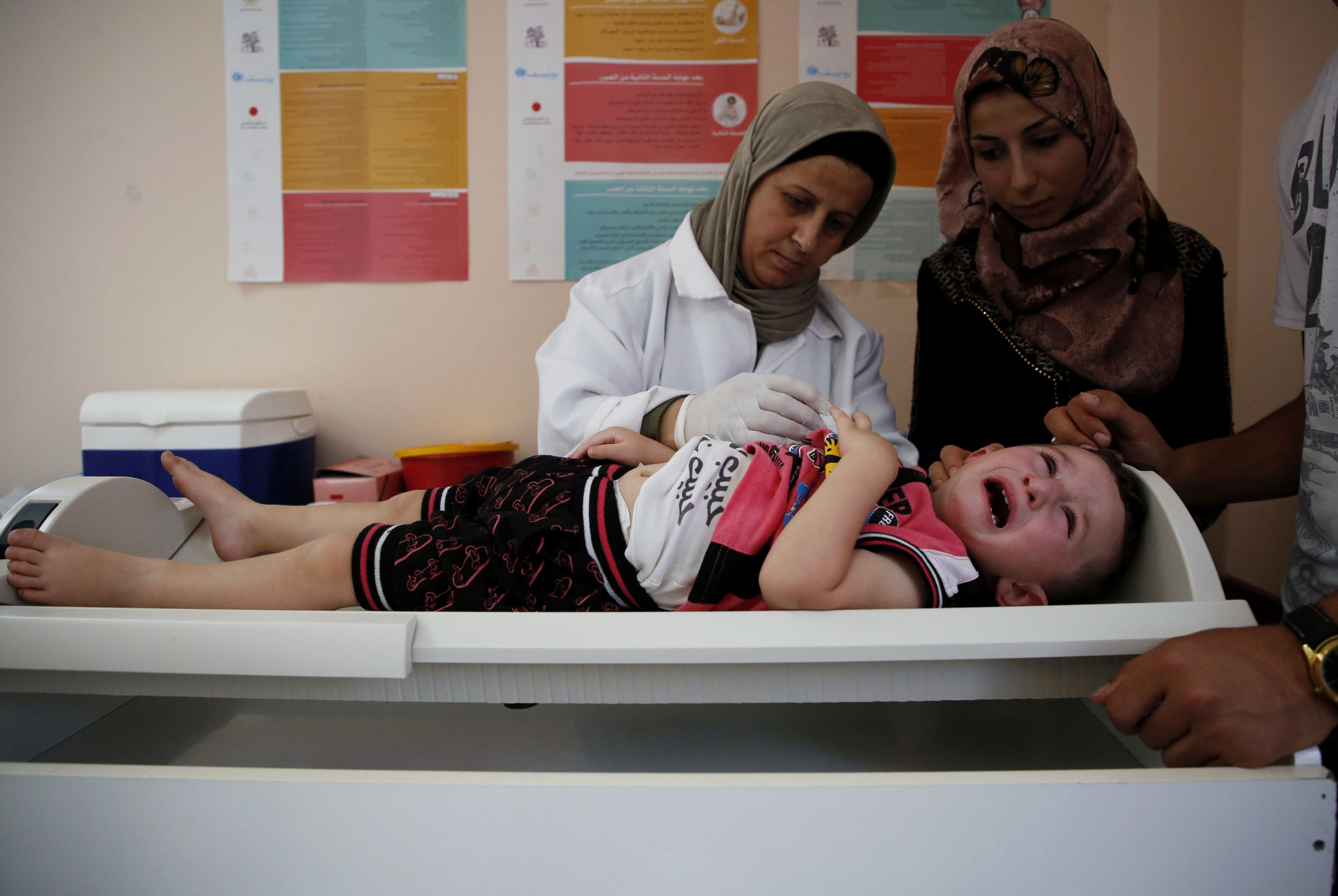 A Palestinian child receives medical check ups and aid from the UNRWA mobile team on the outskirts of the southern West Bank city of Hebron on August 9, 2018. CREDIT: Hazem Bader/AFP/Getty Images.