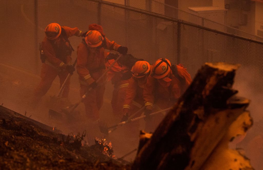 An inmate fire crew clears brush and puts out hotspots to protect an elementary school that almost caught fire at the Holy Fire in Lake Elsinore, California, southeast of Los Angeles, on August 9, 2018. CREDIT: ROBYN BECK/AFP/Getty Images