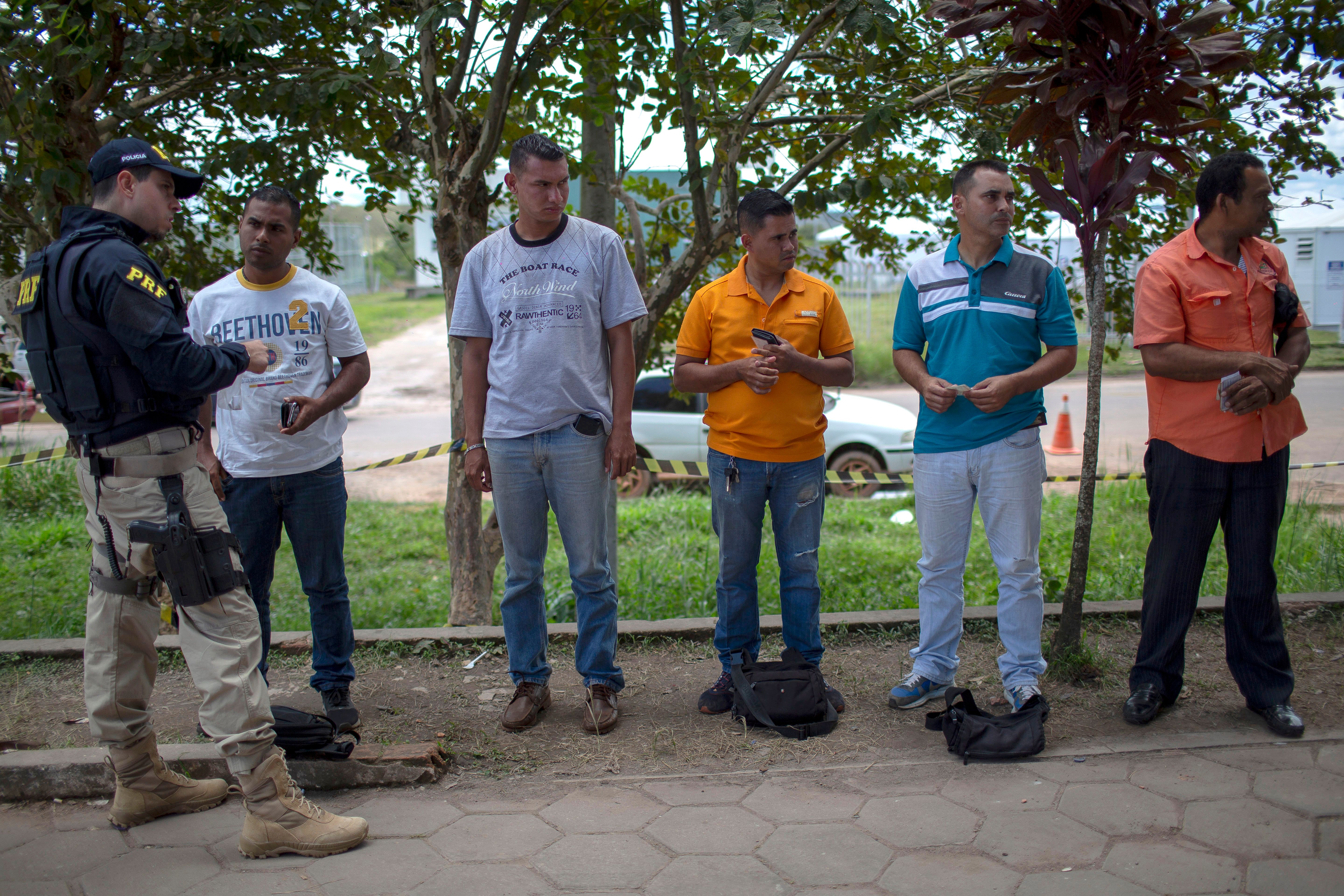 Venezuelan immigrants present their identification cards to a Brazilian Federal Road Police officer at the Brazilian Immigration Centre in the border city of Pacaraima, Roraima State, Brazil, on August 20, 2018. (PHOTO CREDIT: Mauro Pimentel/AFP/Getty Images)