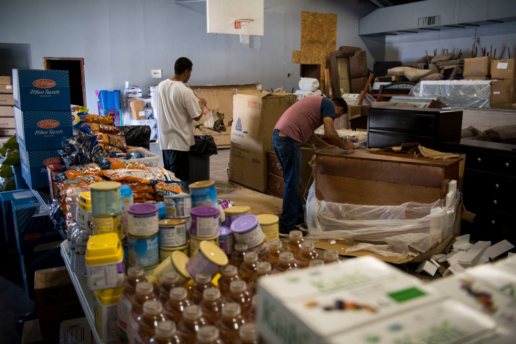 Bethel Baptist Church Lead Pastor Jaime Garcia unloads donated furniture for people who lost their homes and belongings in Hurricane Harvey into his church's gym, which has served as a warehouse for donated goods for his community over the past year, on June 30, 2018 in East Houston, Texas. CREDIT: Carolyn Van Houten/The Washington Post via Getty Images