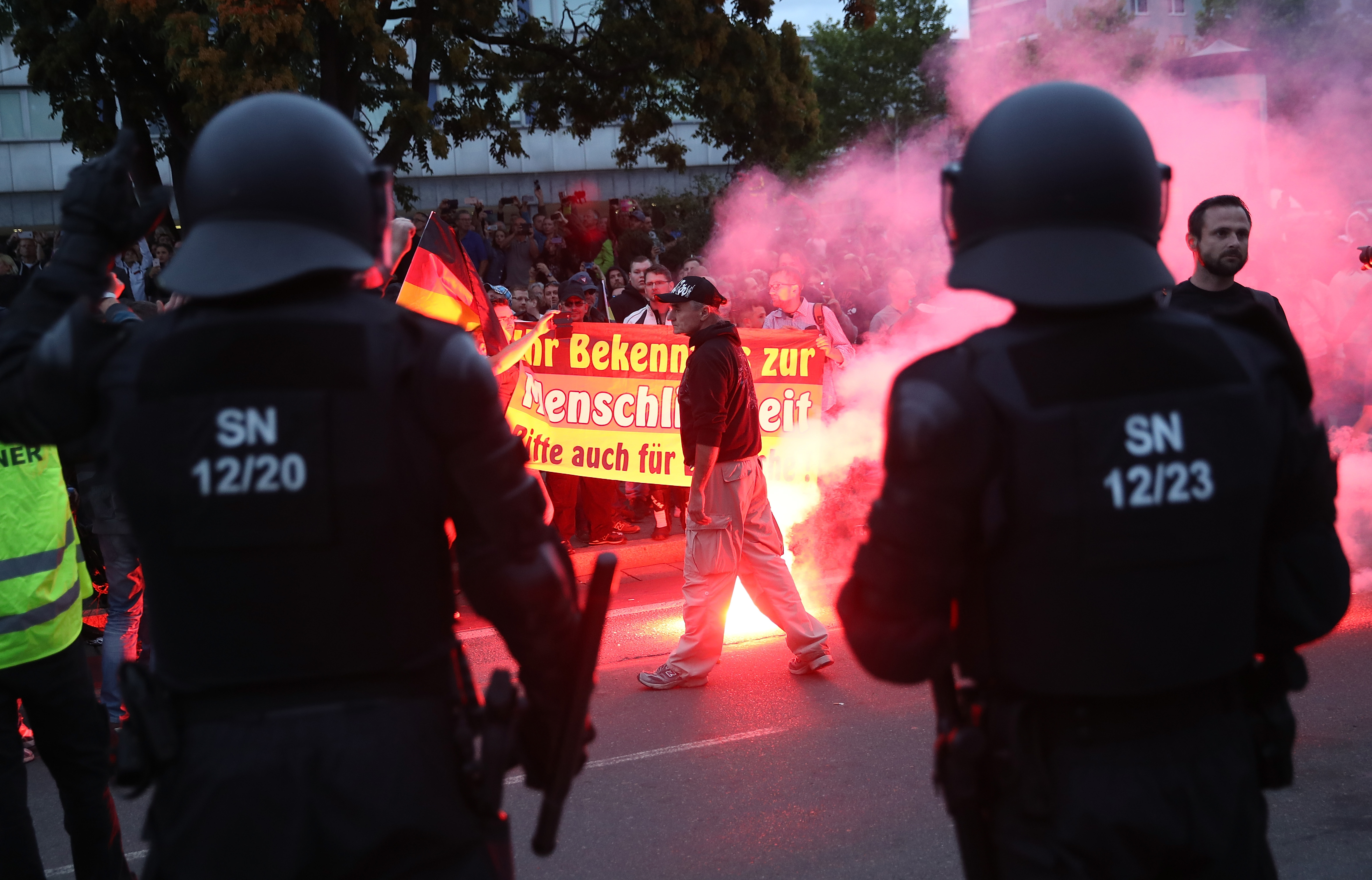 CHEMNITZ, GERMANY - AUGUST 27: Riot police watch right-wing supporters who had gathered the day after a man was stabbed and died of his injuries on August 27, 2018 in Chemnitz, Germany. A German man died after being stabbed in the early hours yesterday following an altercation, leading a xenophobic mob of approximately 800 people to take to the streets. Today left-wing and right-wing groups of over a thousand people each confronted each other as riot police stood in between. Police announced today they have arrested a Syrian man and an Iraqi man as suspected perpetrators of the stabbing. (Photo by Sean Gallup/Getty Images)