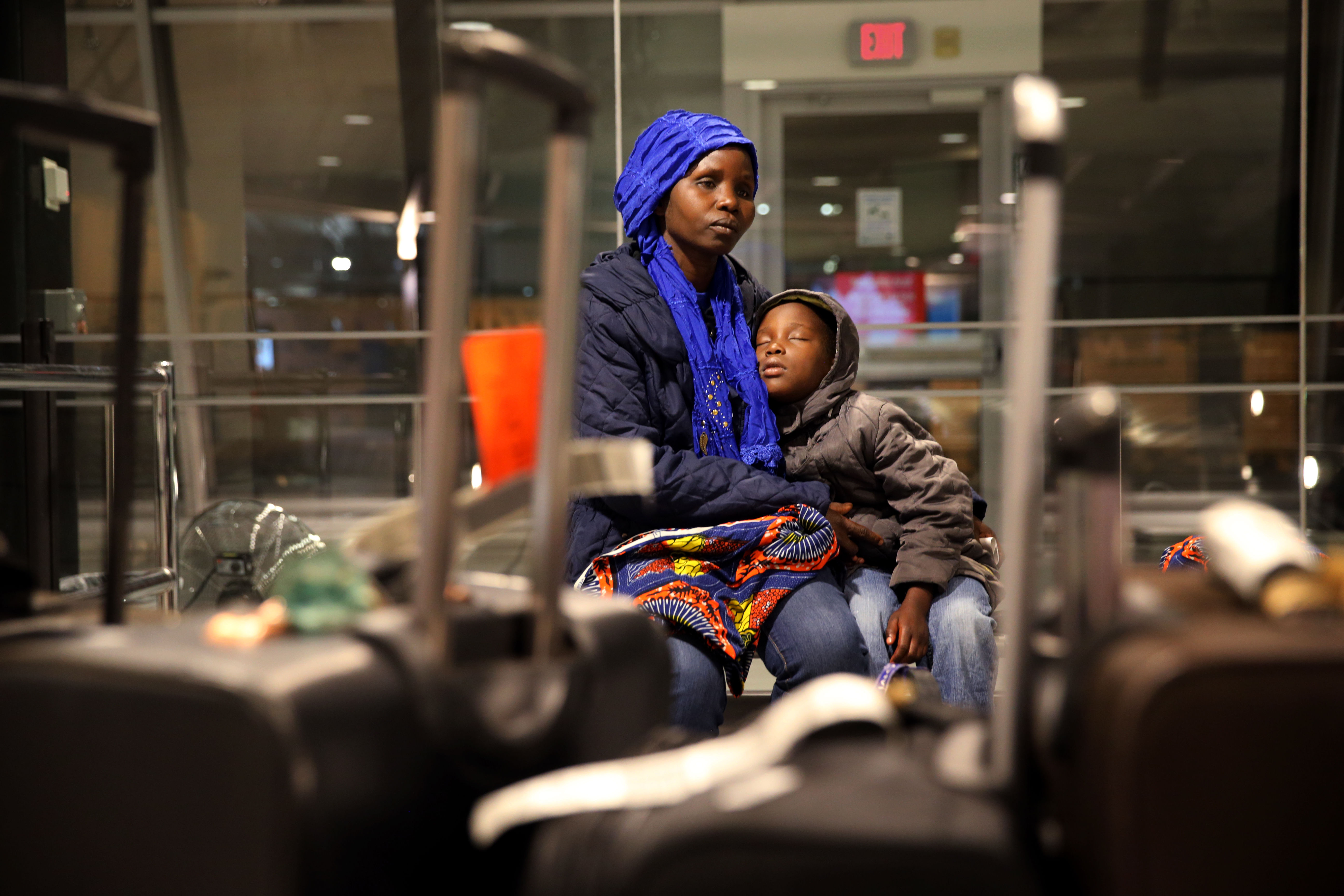 Vanisi Uzamukunda comforts her sleepy daughter Sarah, 7, while waiting for their baggage at the Manchester Boston Regional Airport in Manchester, NH on Feb. 3, 2017. The family of seven from the Democratic Republic of the Congo arrived a few days after President Trump signed an order barring any refugees for 120 days. (Photo Credit: Craig F. Walker/The Boston Globe via Getty Images)